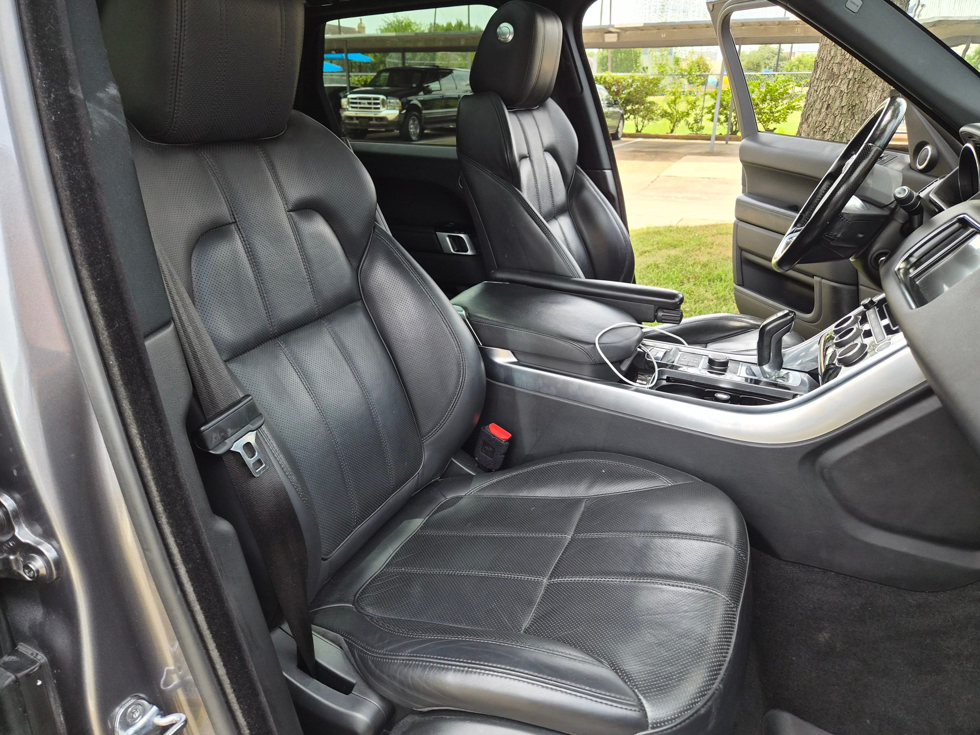 View of black perforated leather front seats and center console.