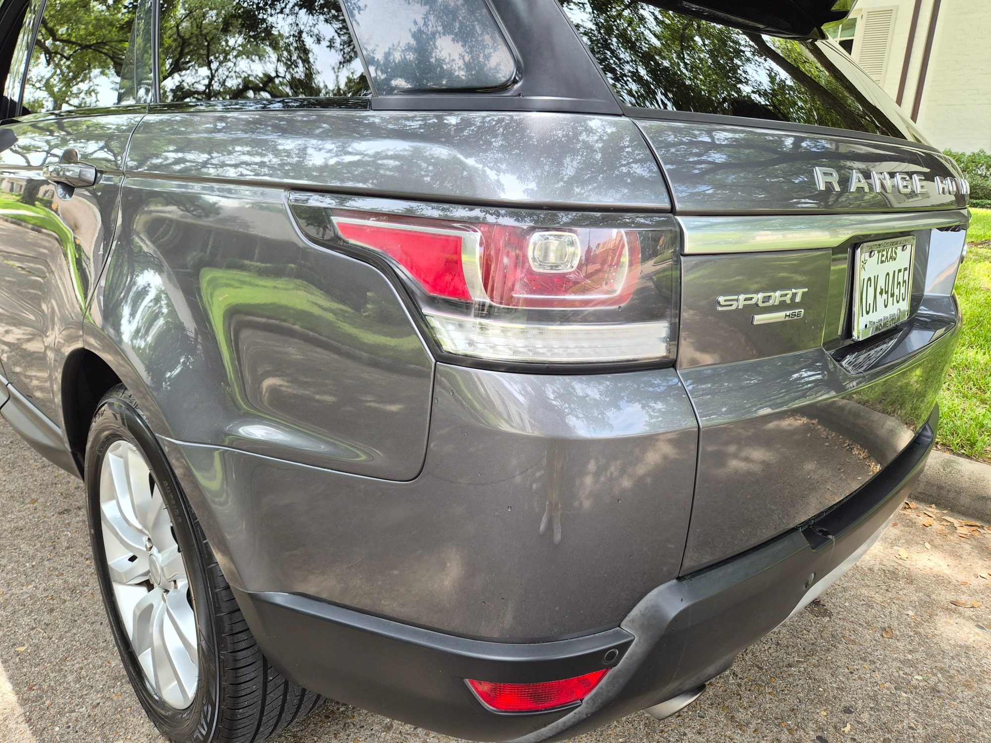 Rear left quarter view showing taillight, badging, and wheel of a gray Range Rover Sport.
