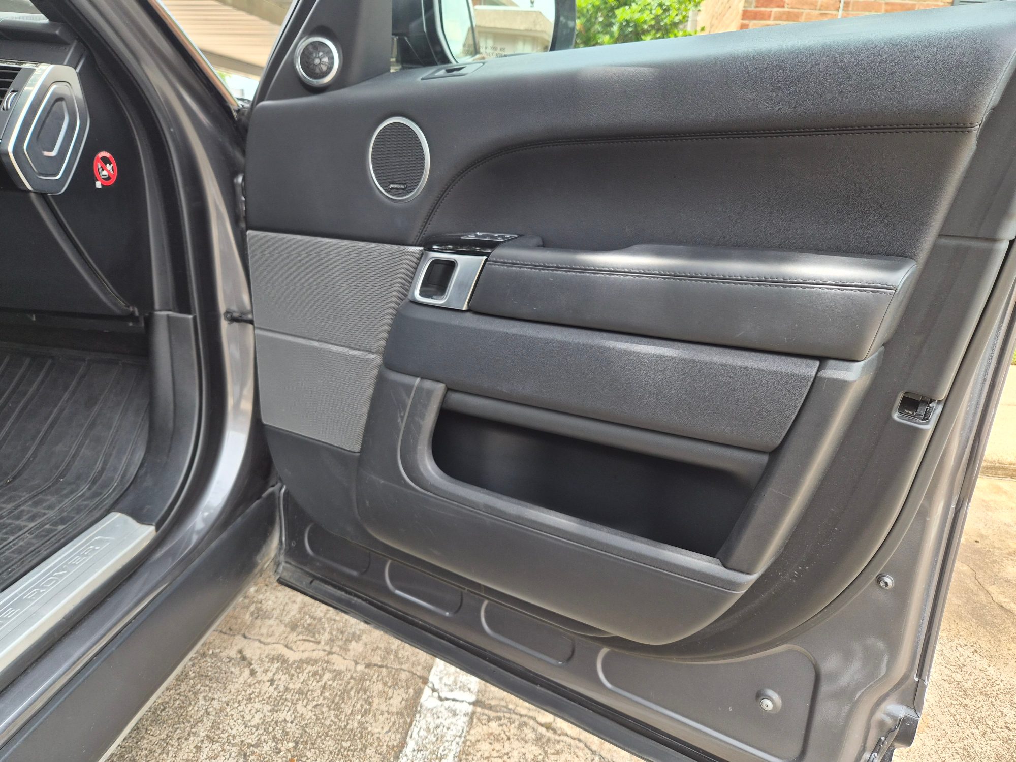 Driver side interior door panel showing speakers and armrest.