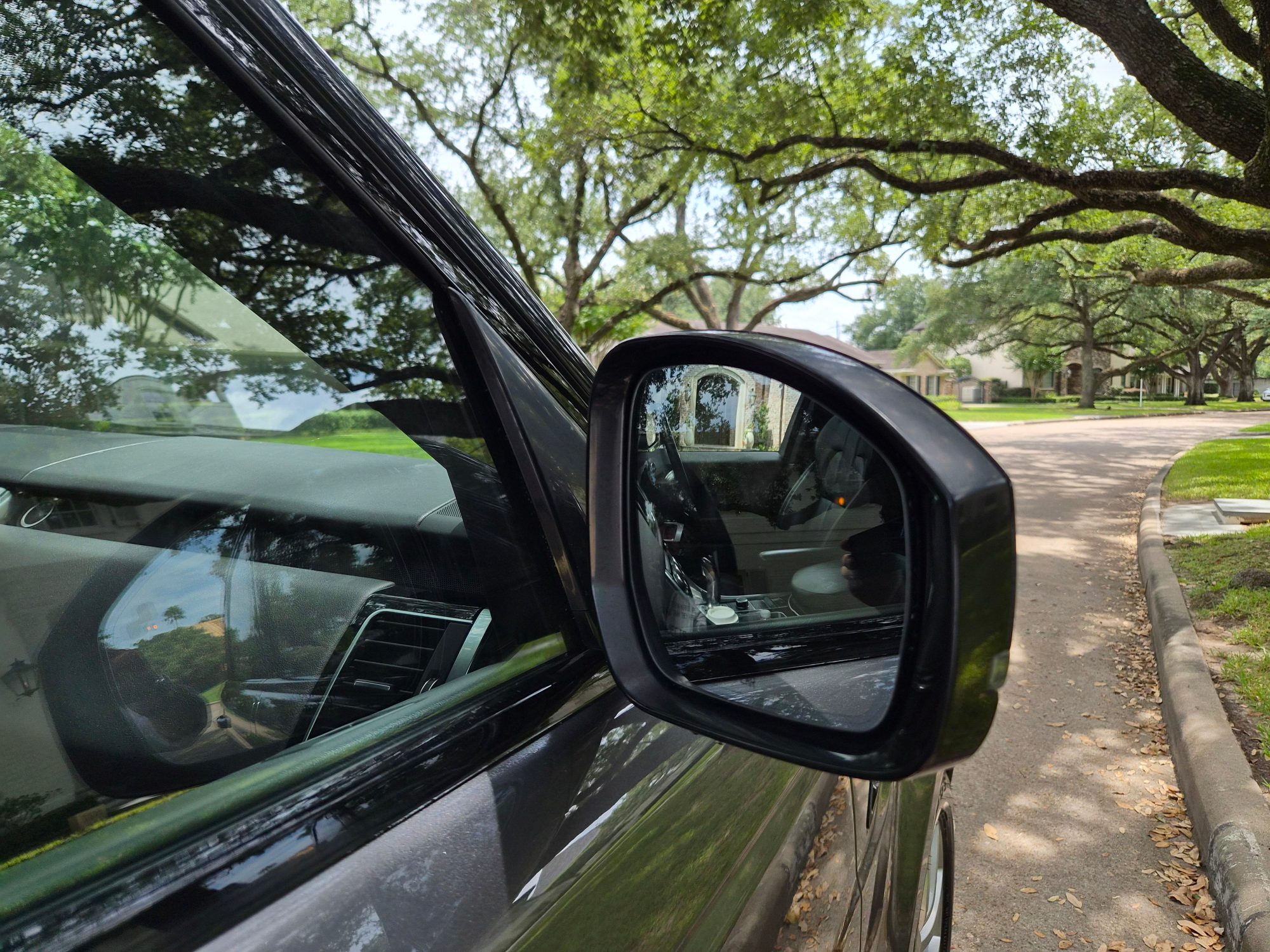 Close-up of the driver side exterior rearview mirror and window glass.