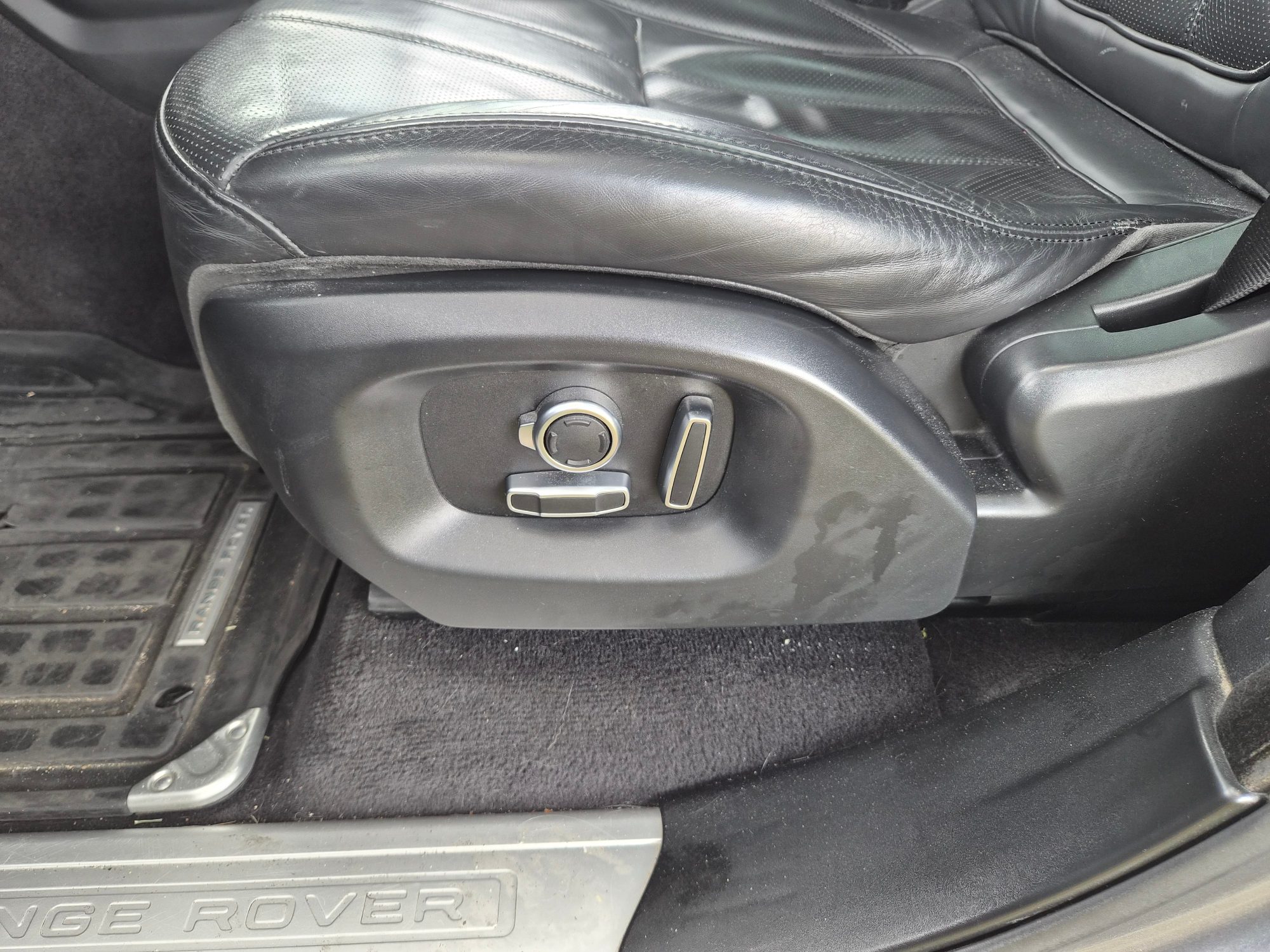 Detail view of electric seat adjustment controls and leather upholstery.