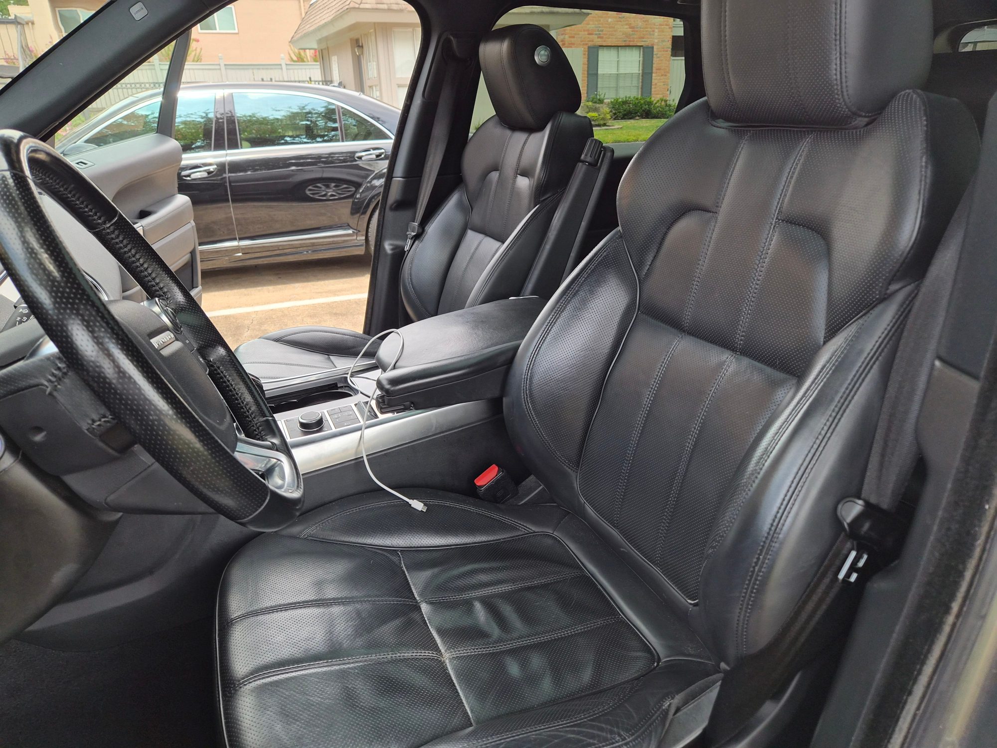 View of the front cabin featuring black leather seats and steering wheel.