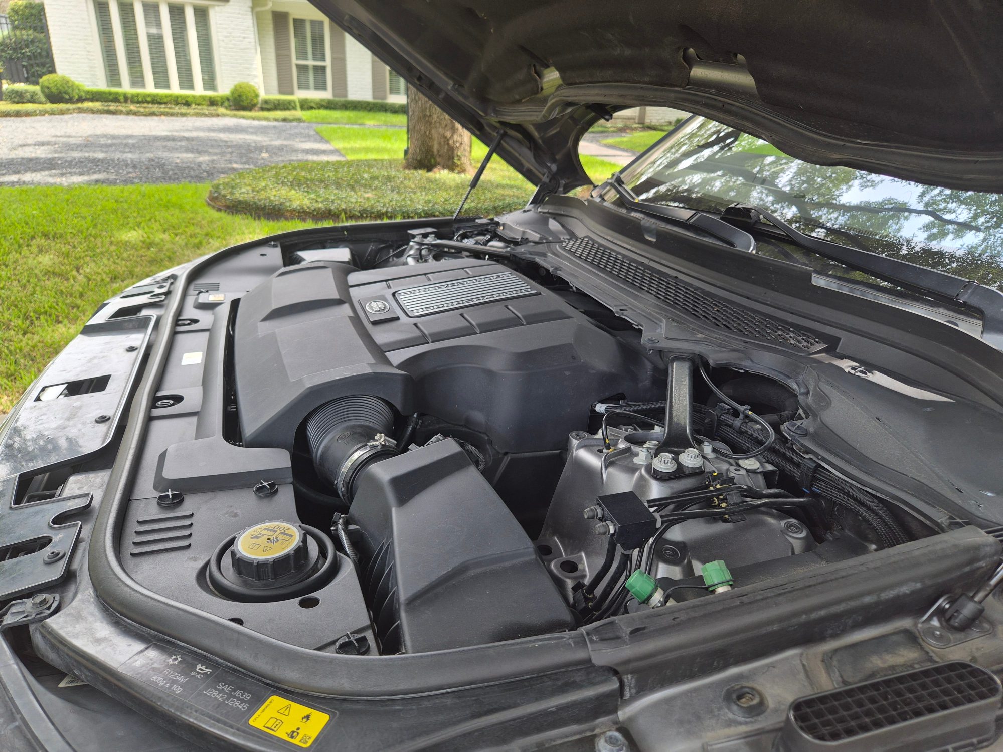 Supercharged V8 engine bay with hood open.