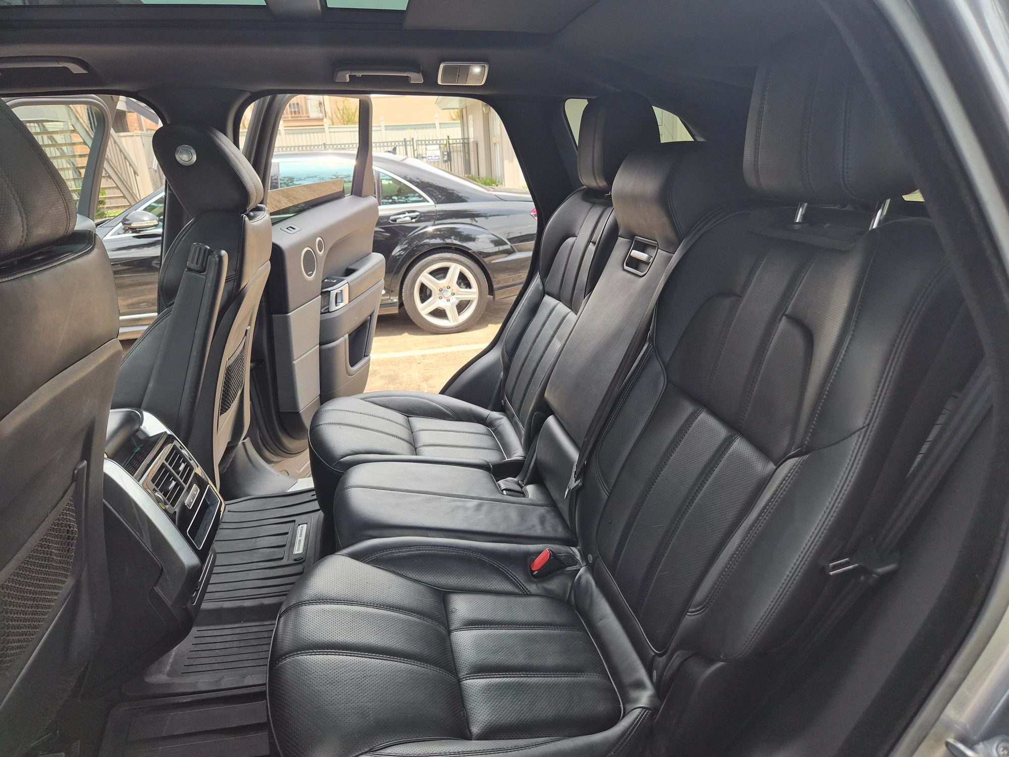 Rear passenger cabin with black leather seats and climate vents.