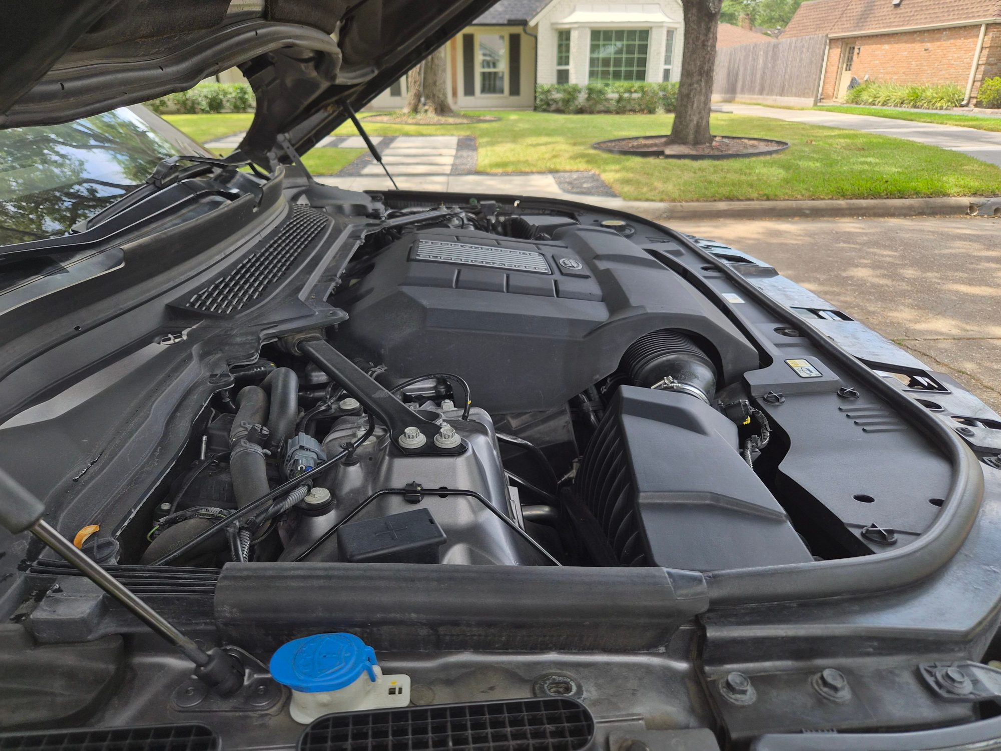 View of the supercharged engine bay with plastic covers intact.
