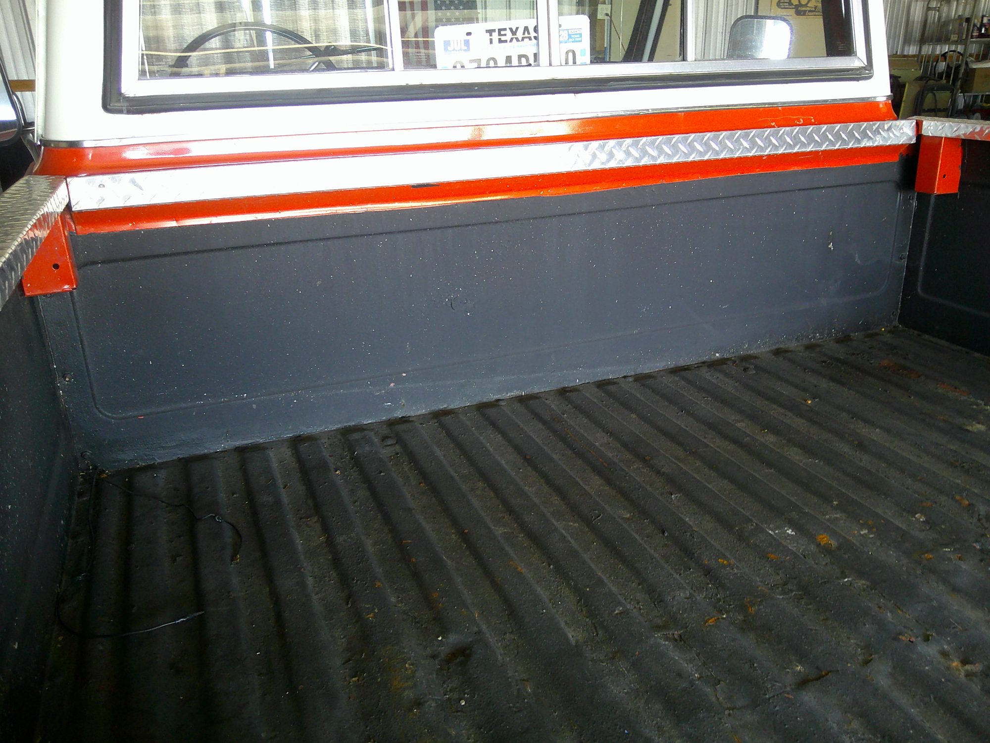 View of the pickup truck bed with black liner and rear window
