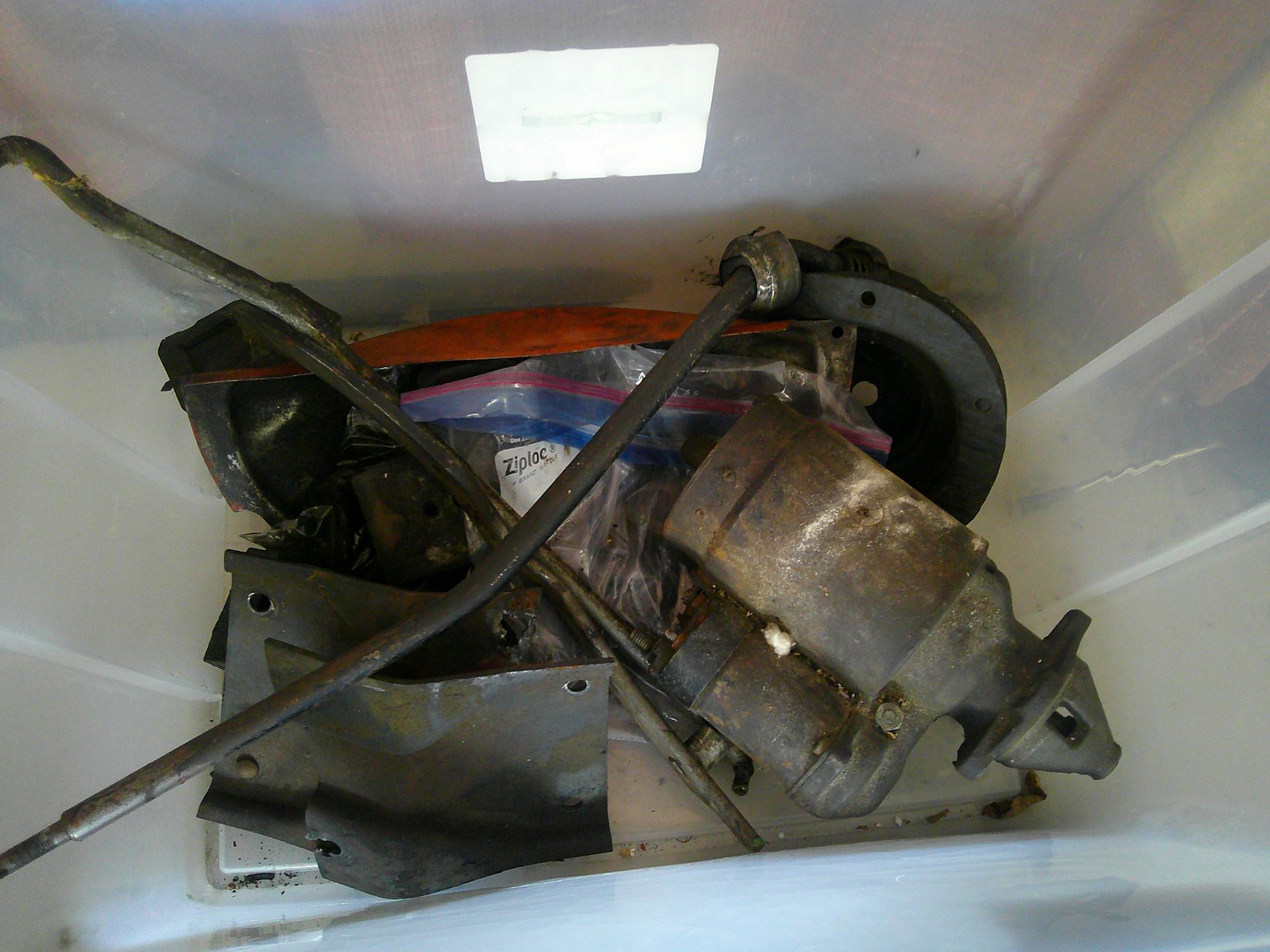Assorted mechanical components and hardware in a storage bin.