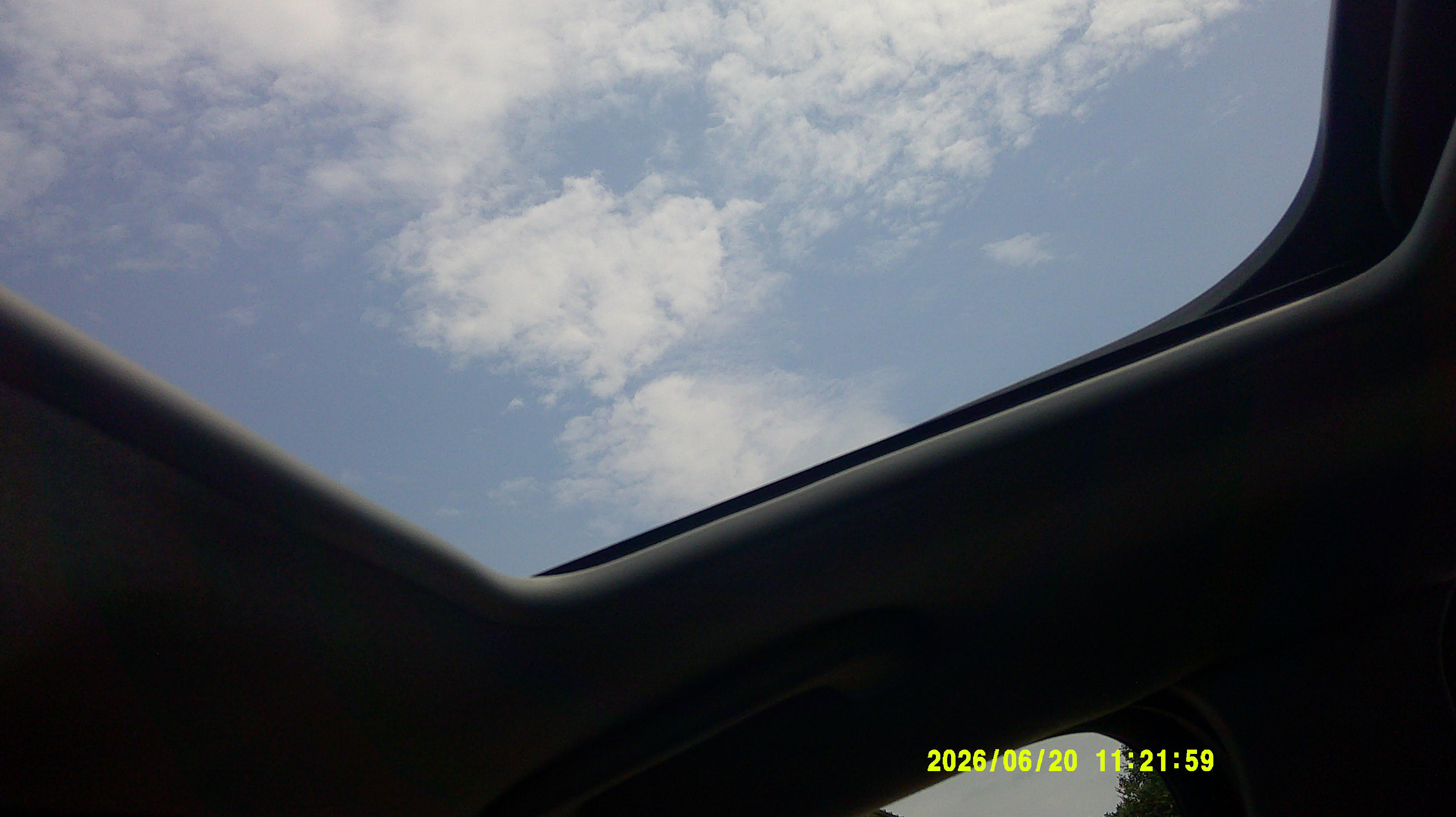 View of the sky through an open car sunroof from inside the cabin.
