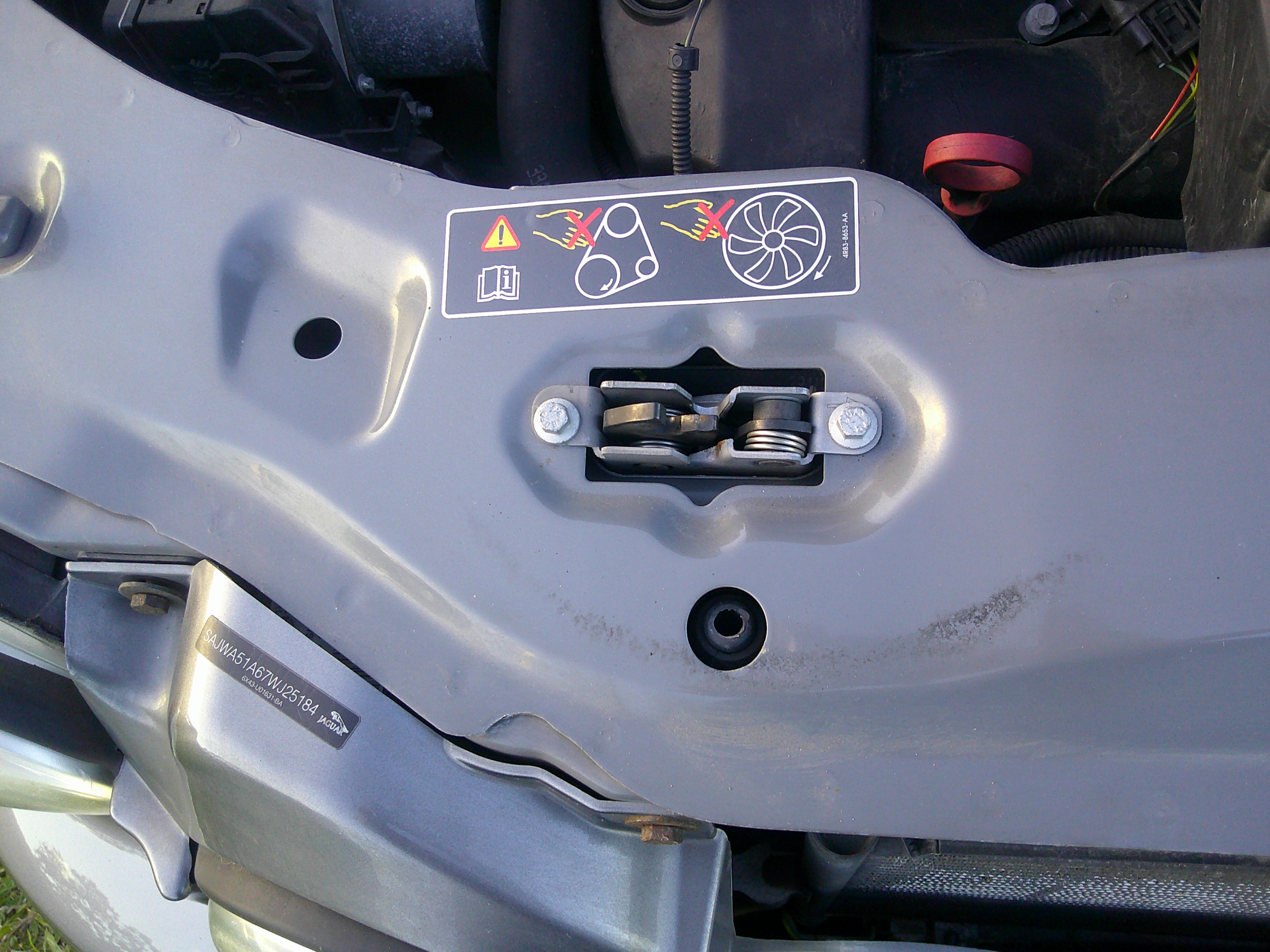 View of the upper radiator support with VIN sticker and safety decals.