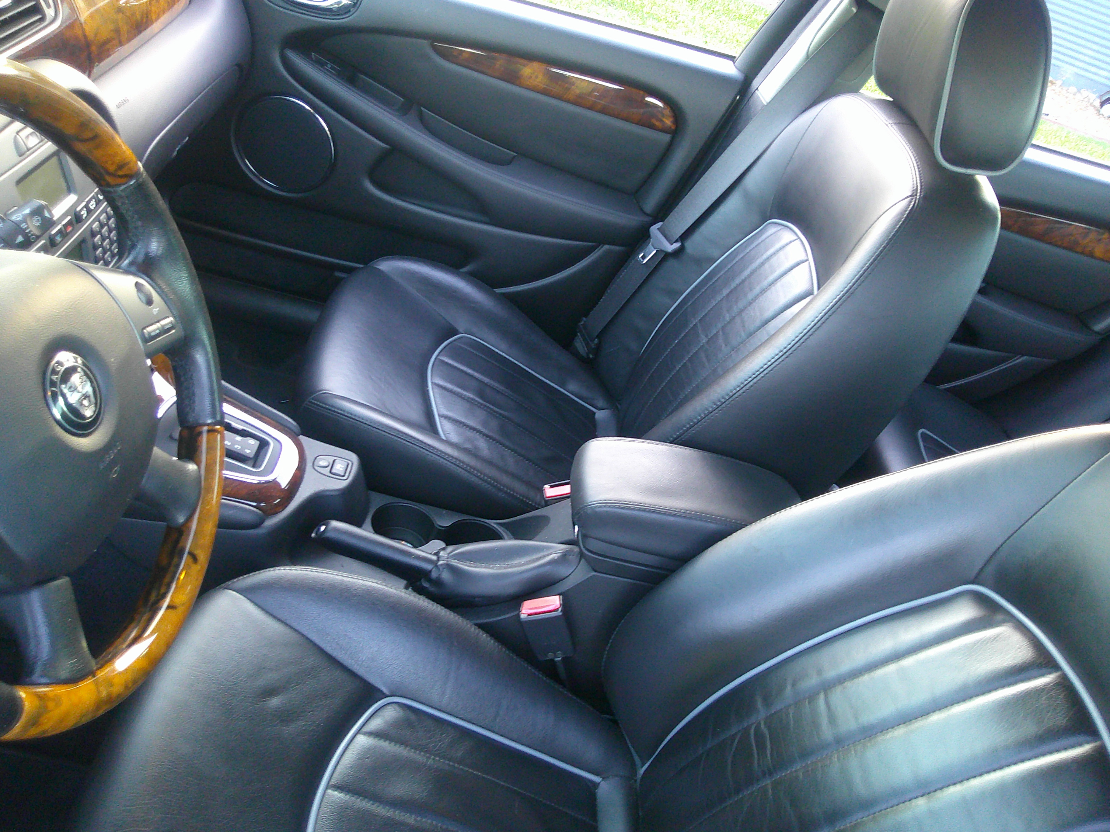 Black leather front seats with wood grain trim and steering wheel.