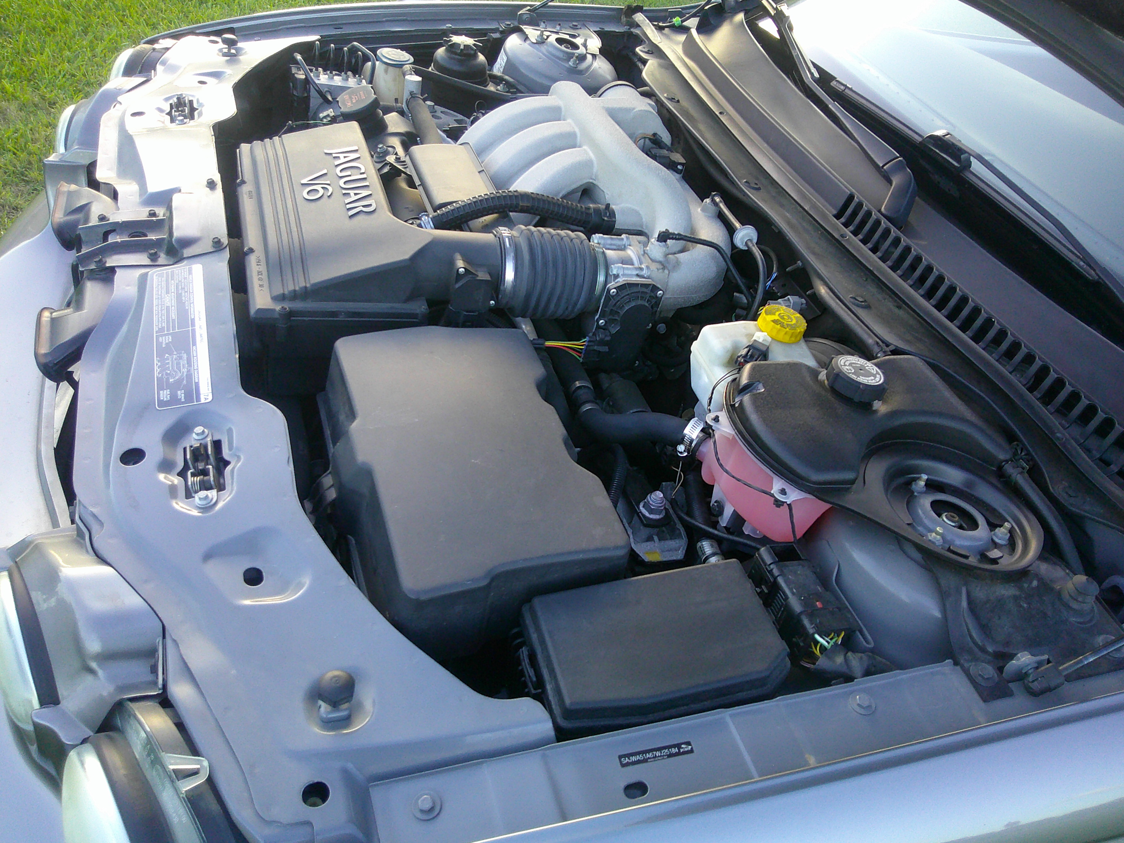 View of the Jaguar V6 engine bay with intake manifold and fluid reservoirs.