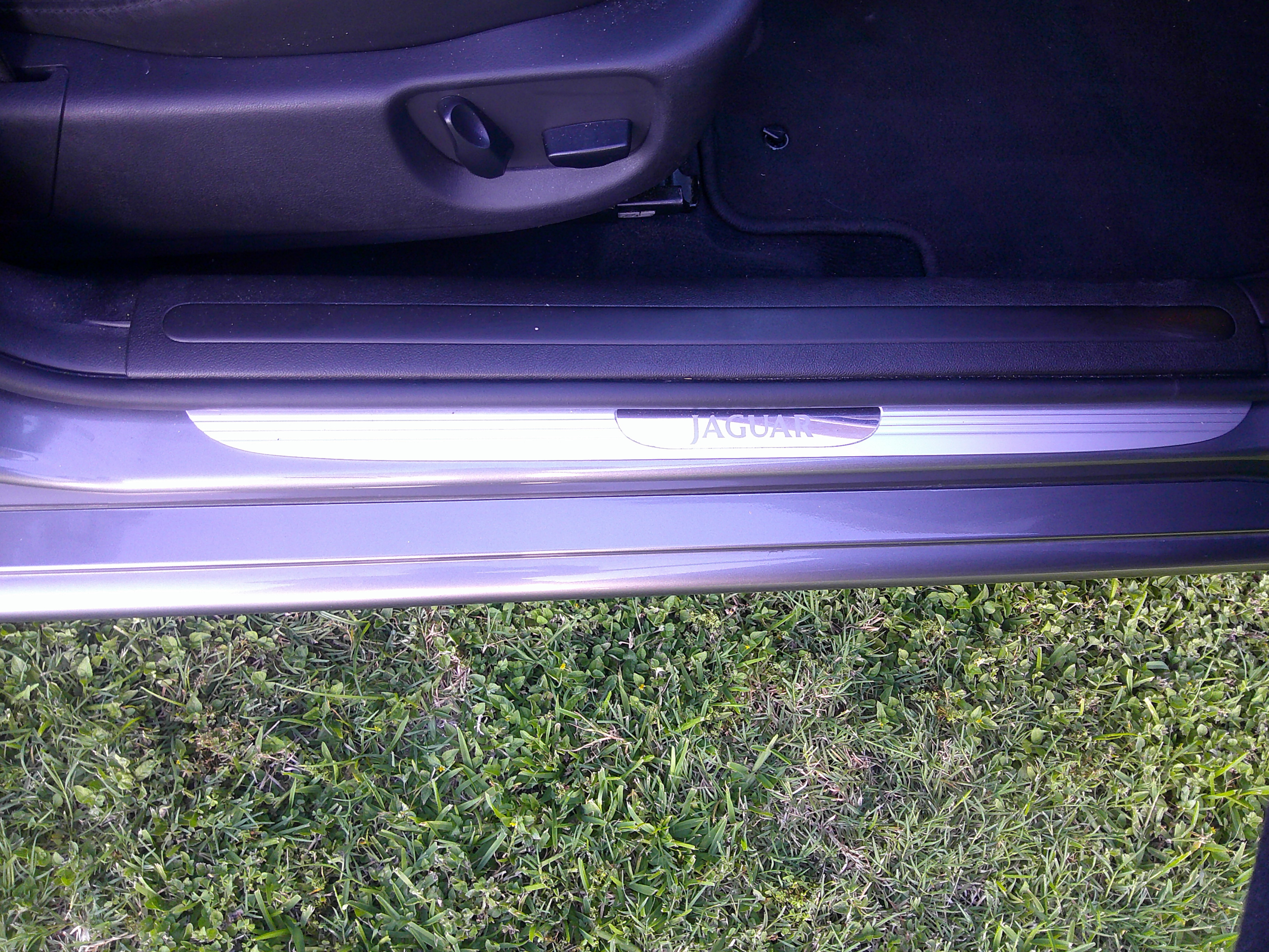 Jaguar branded door sill plate and driver's seat controls.