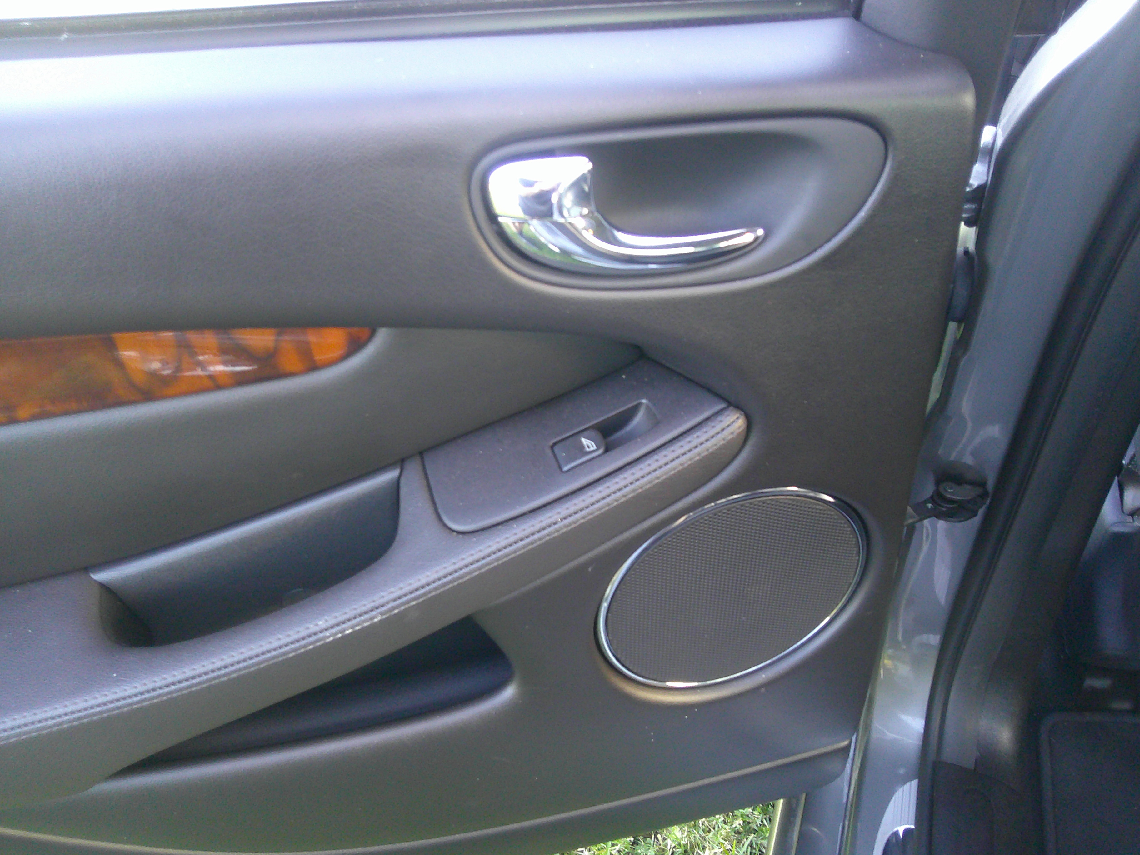 Detail of interior door panel with chrome handle and wood trim