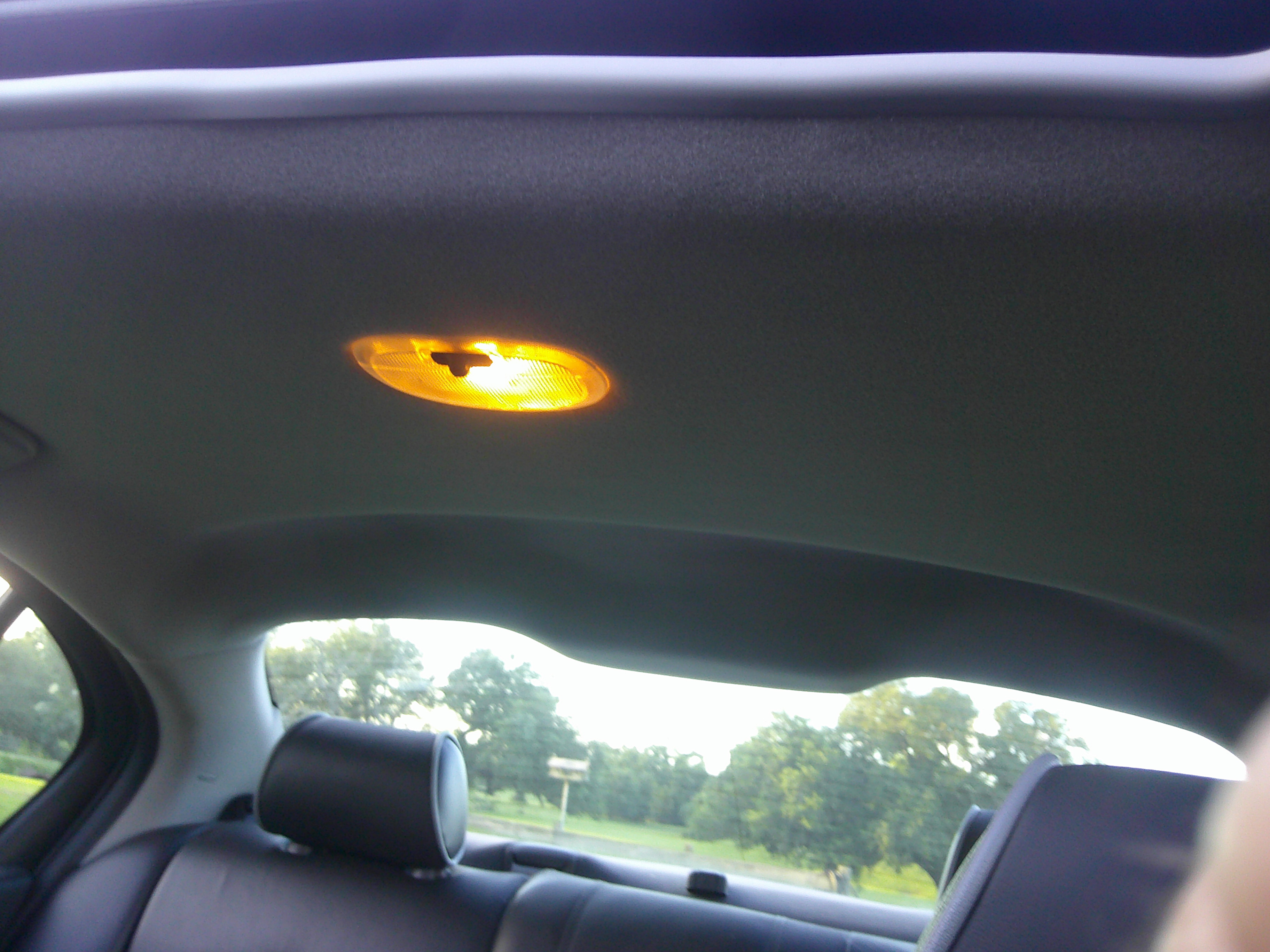 Interior headliner and illuminated dome light with rear seats visible.