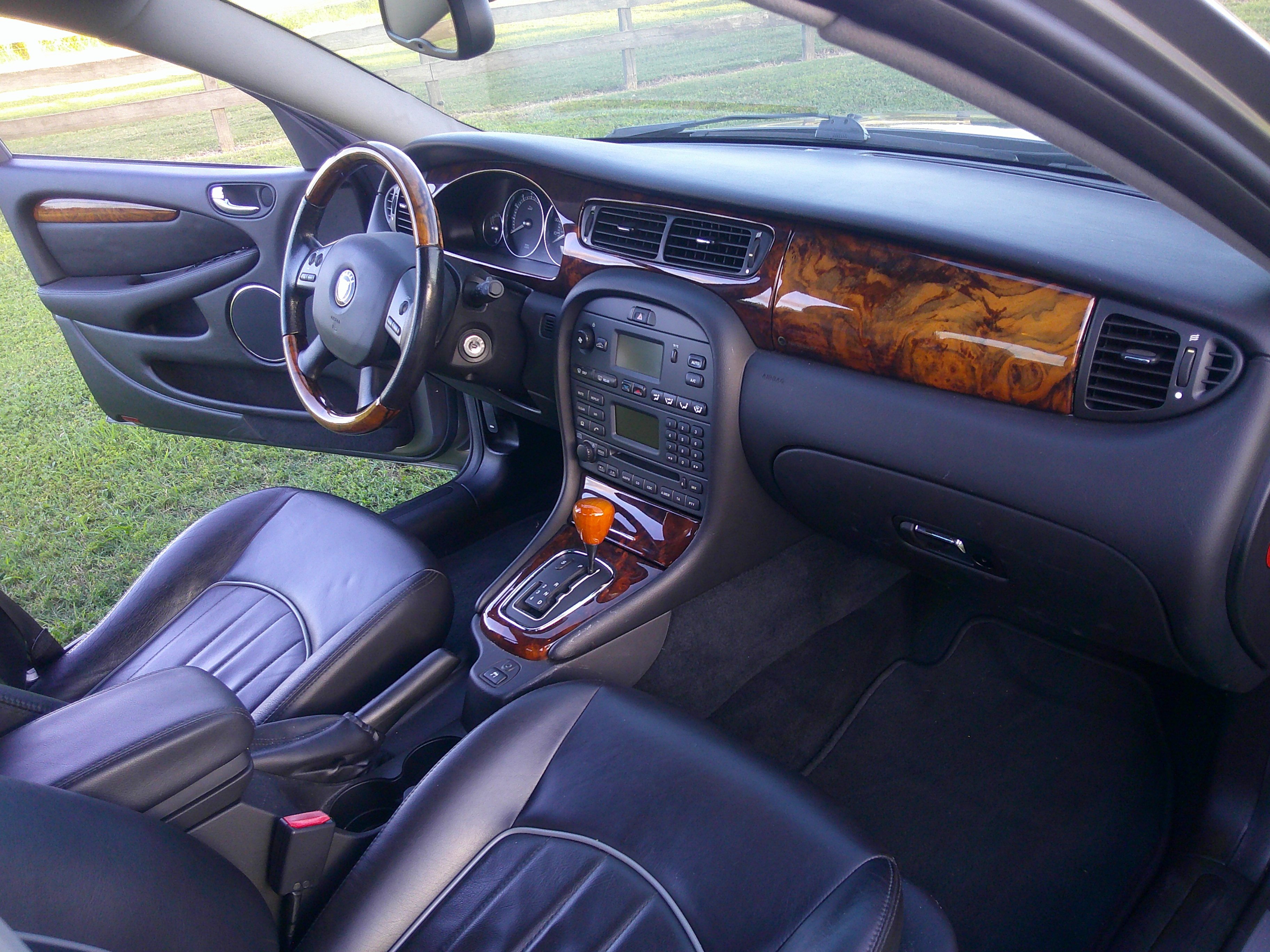 Dashboard and front seats featuring wood trim and black leather upholstery.