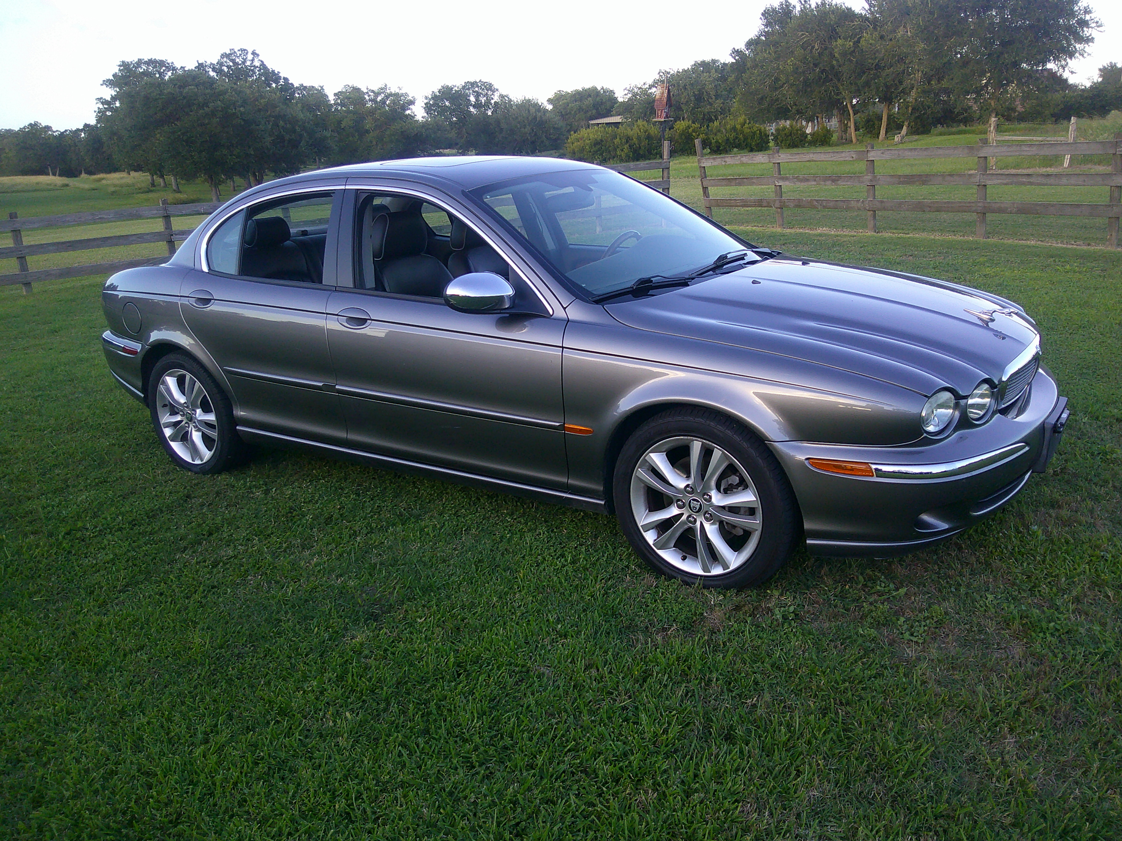Front three-quarter view of a gray Jaguar X-Type sedan on grass.