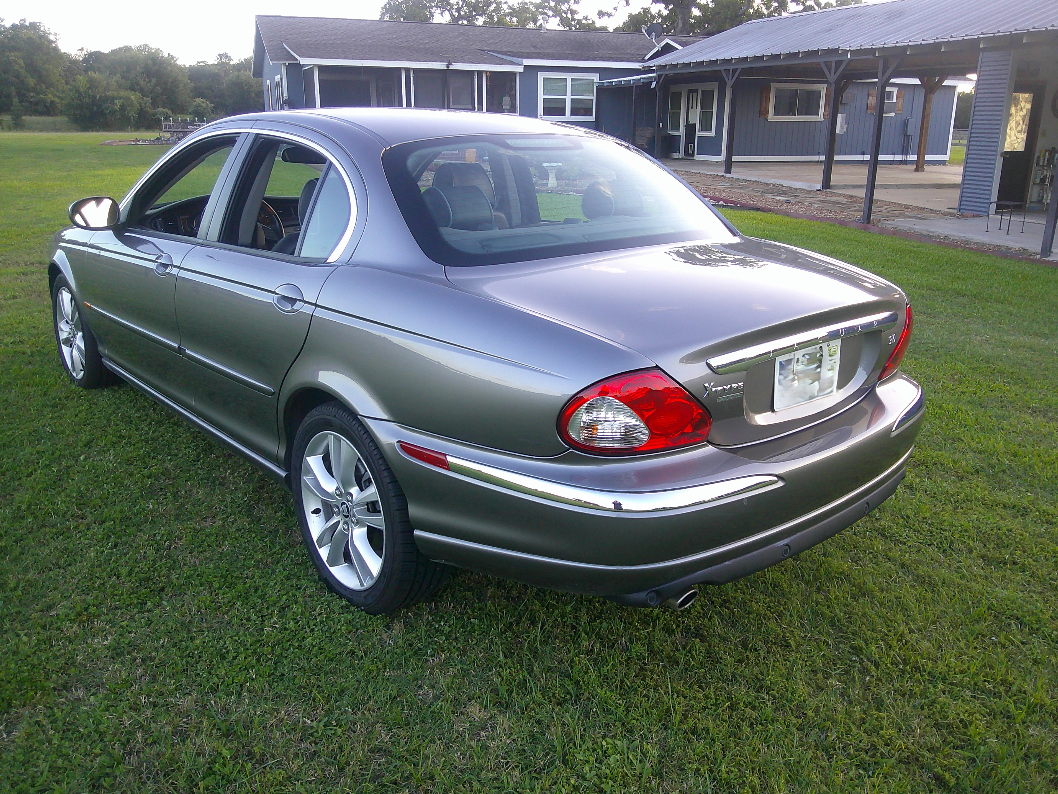 Rear three-quarter view of a grey Jaguar X-Type sedan parked on grass.