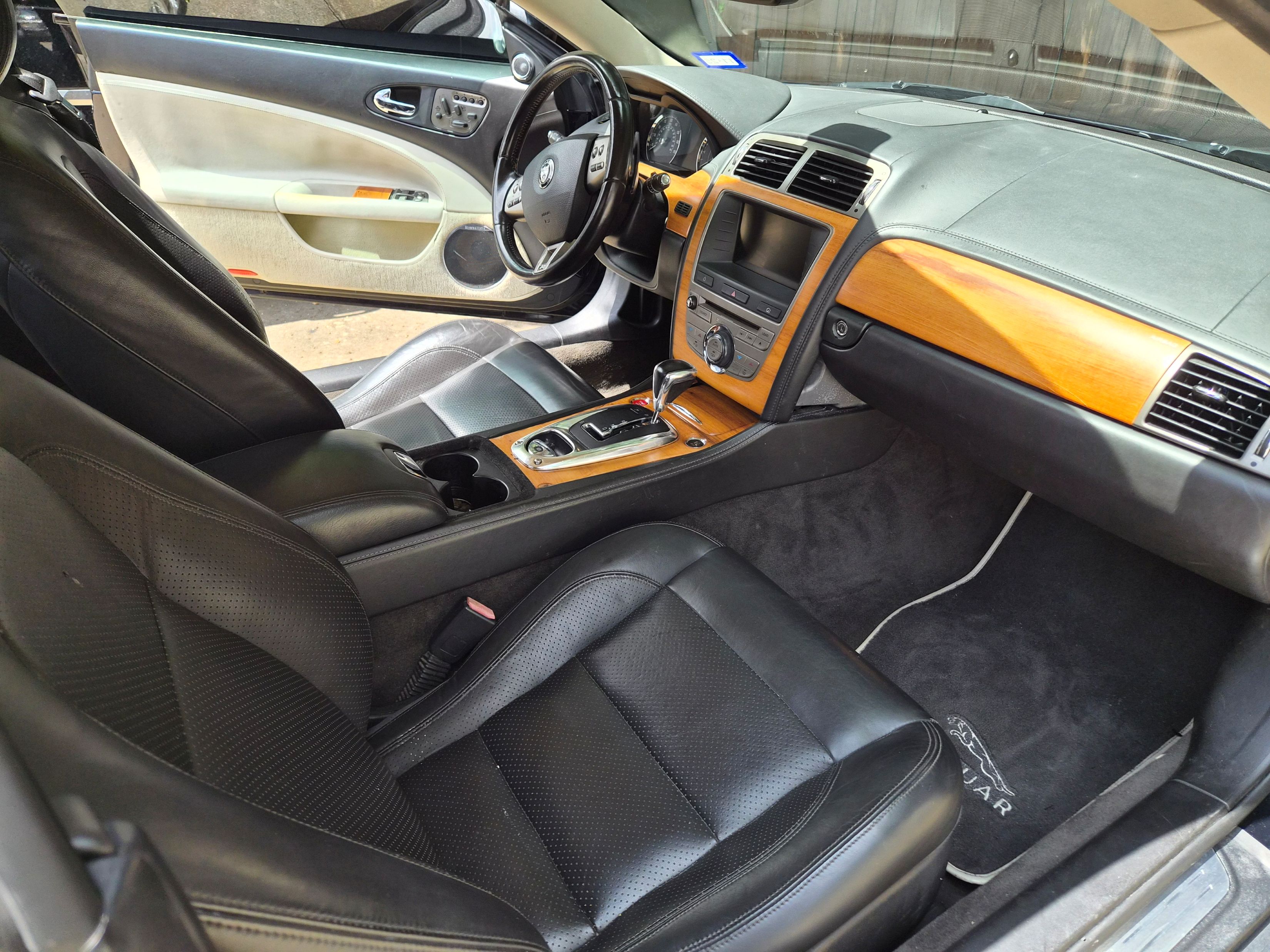 View of front cabin with black leather seats and wood grain trim