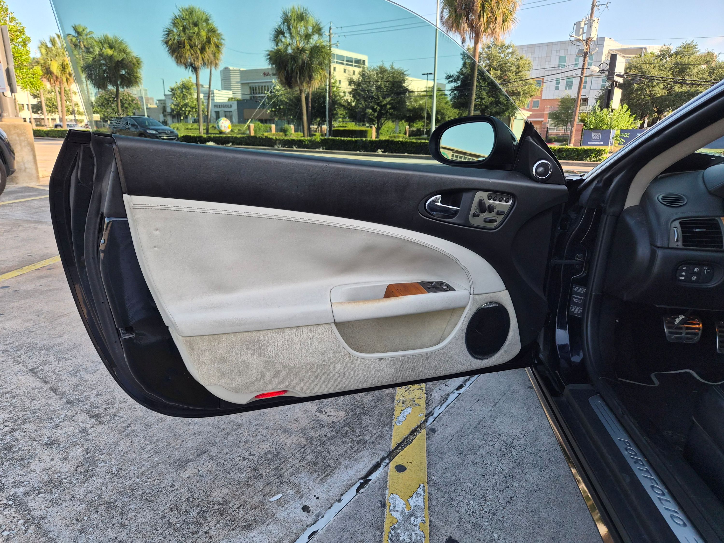 Driver's side interior door panel with two-tone leather and wood trim.