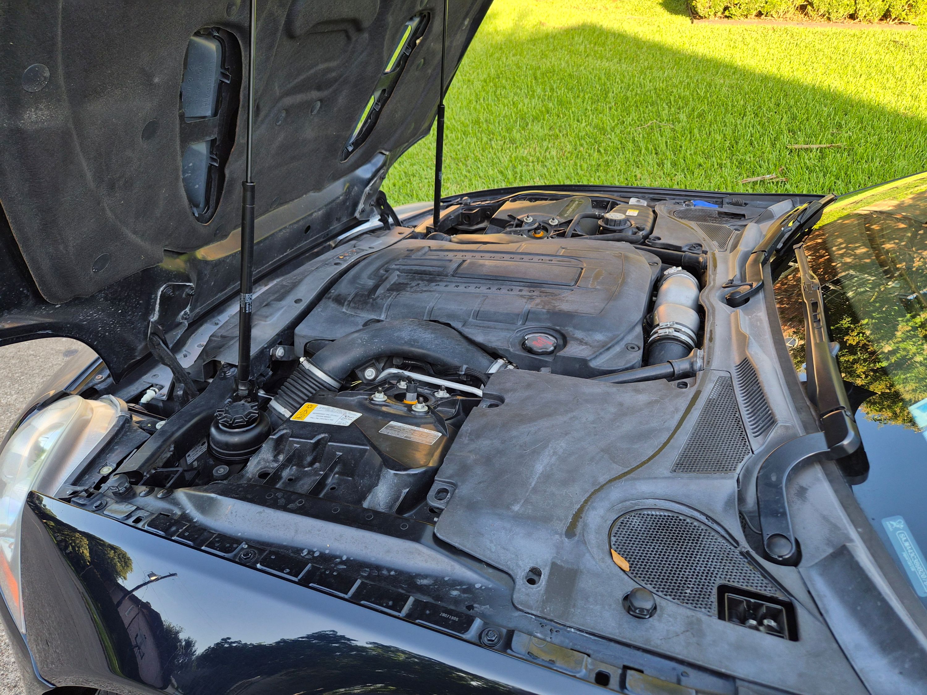 Supercharged V8 engine bay with hood open.