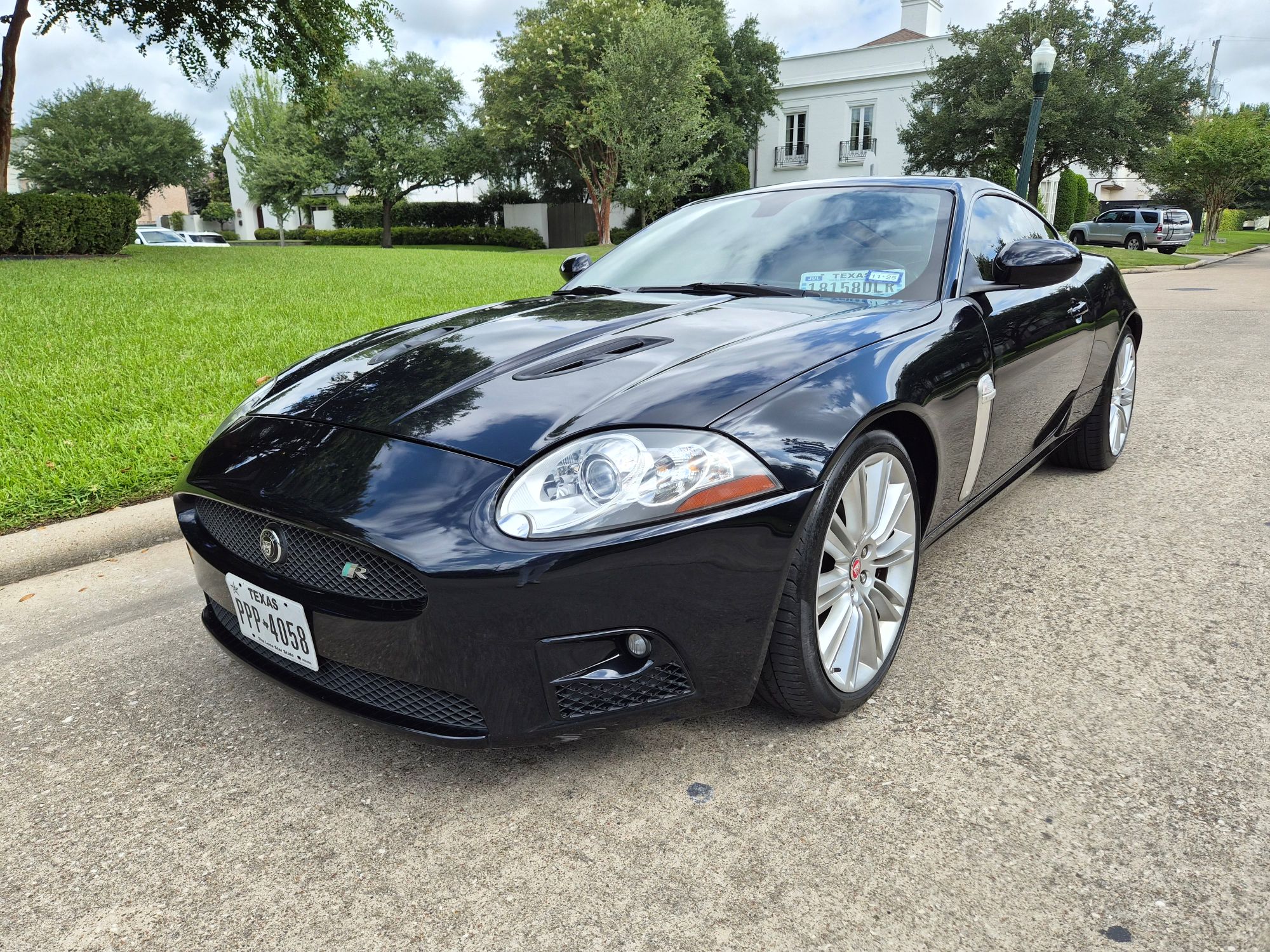 Front three-quarter view of a black Jaguar XKR coupe parked on pavement