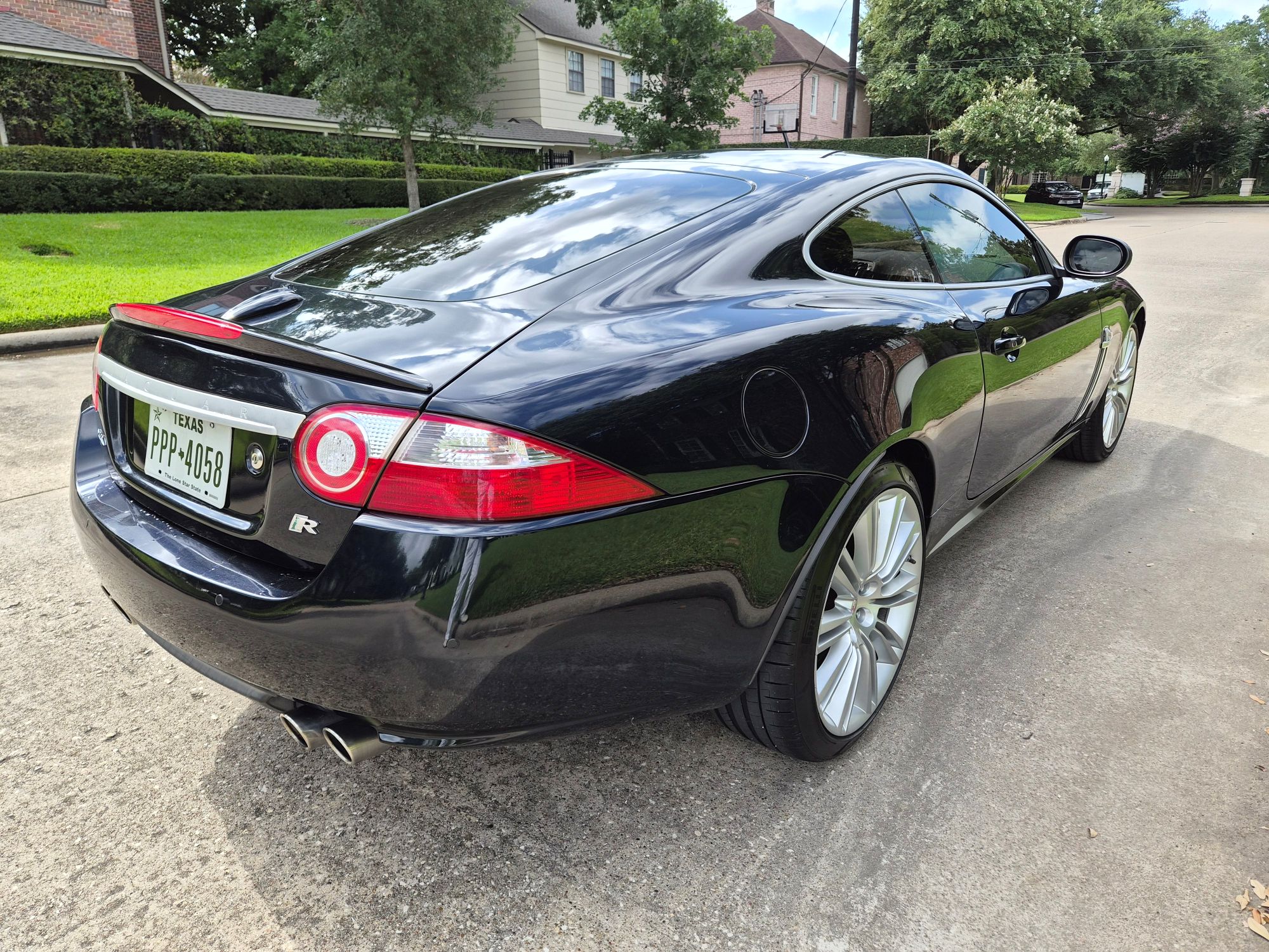Rear three-quarter view of a black Jaguar XKR coupe.
