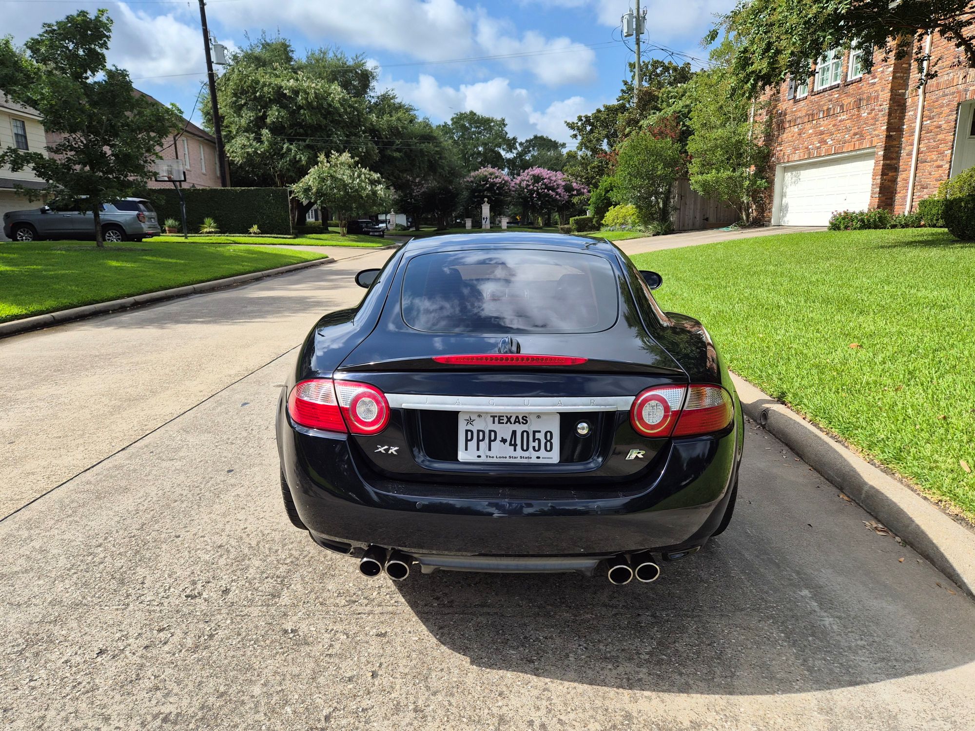 Rear view of black Jaguar XKR parked on a residential street.