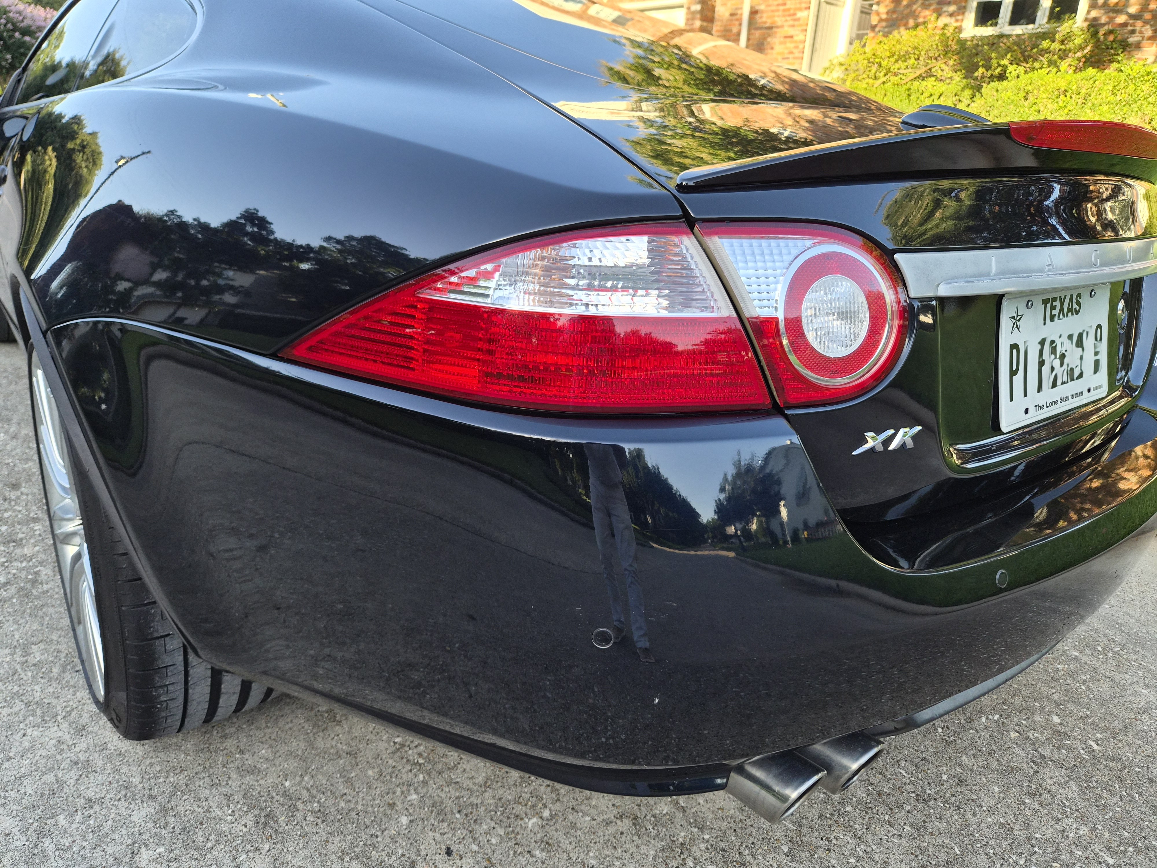 Rear three-quarter view showing taillight, XK badging, and exhaust tips.