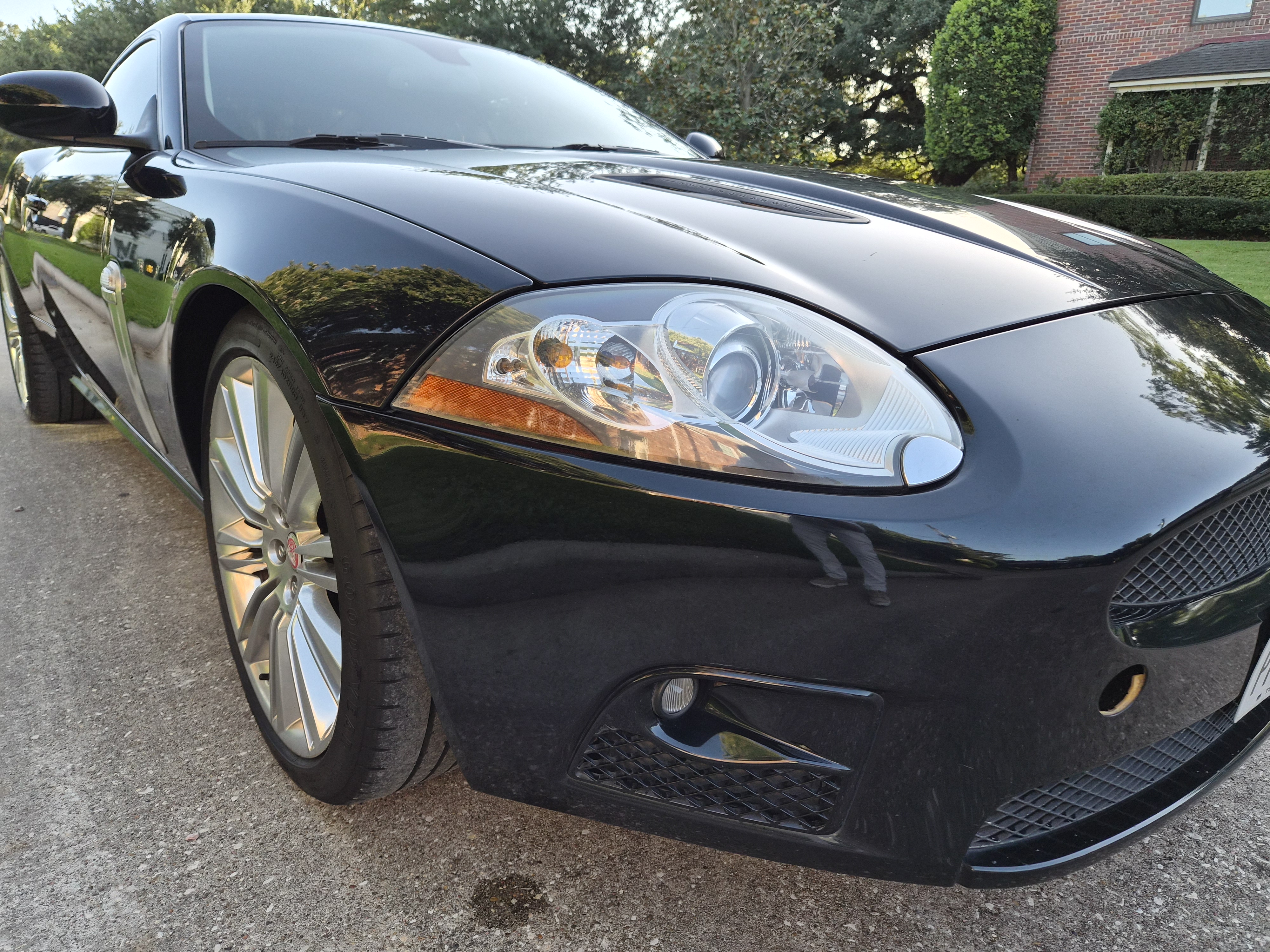 Front three-quarter view of black Jaguar XK showing headlight and wheel detail