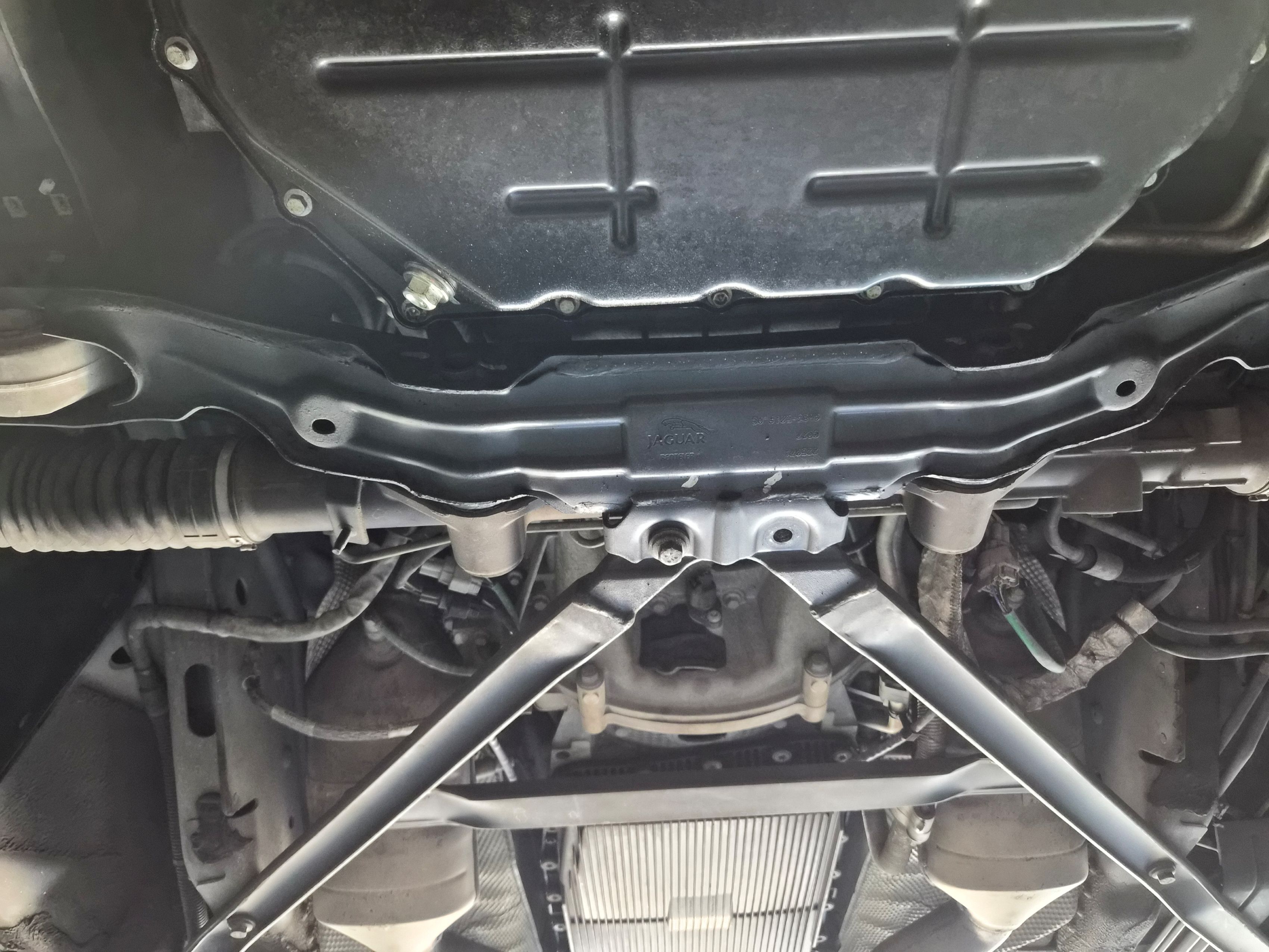 Underbody view of the chassis, crossmember, and oil pan.