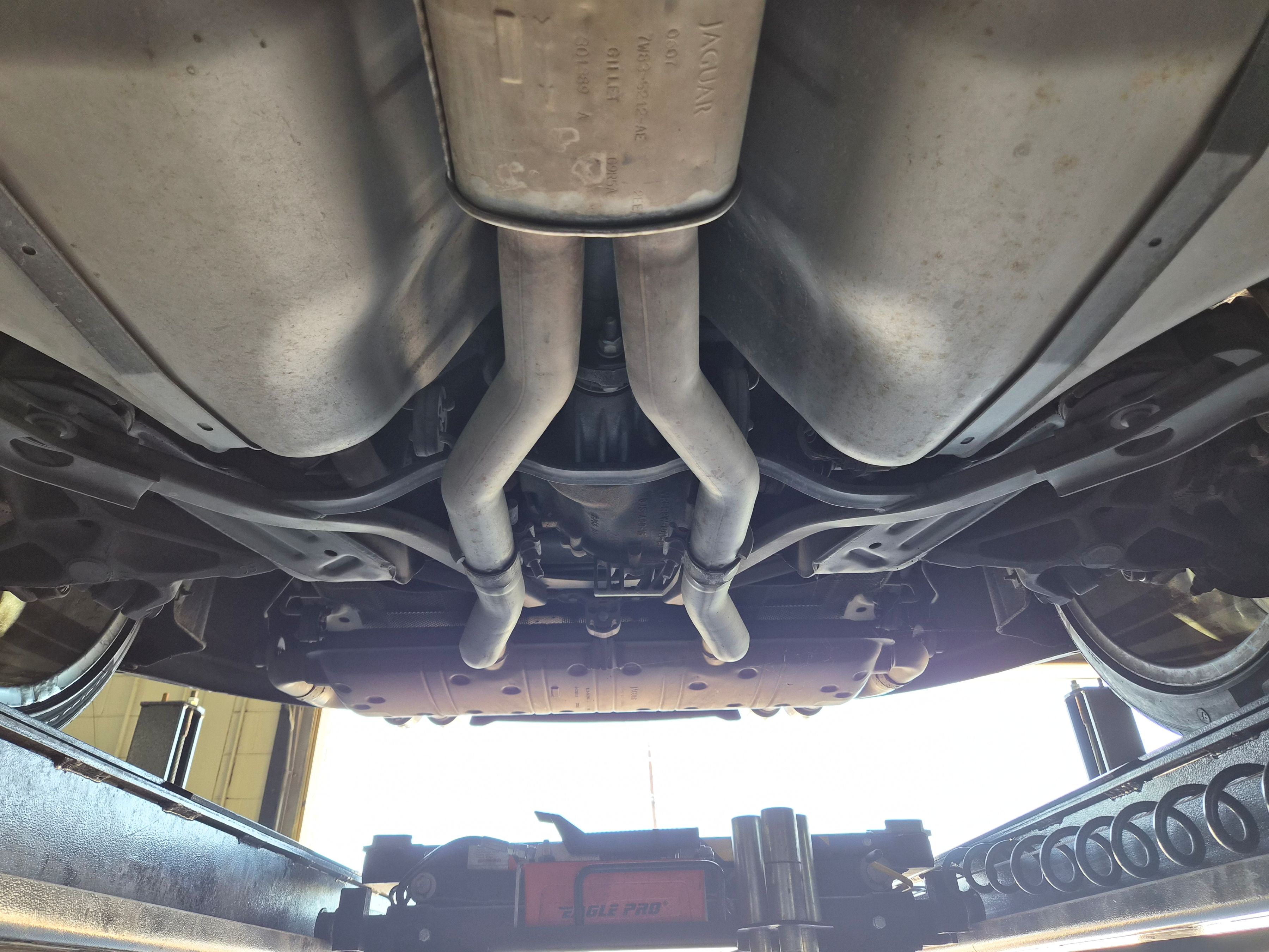 Chassis view showing exhaust system, rear differential, and fuel tanks on a lift.