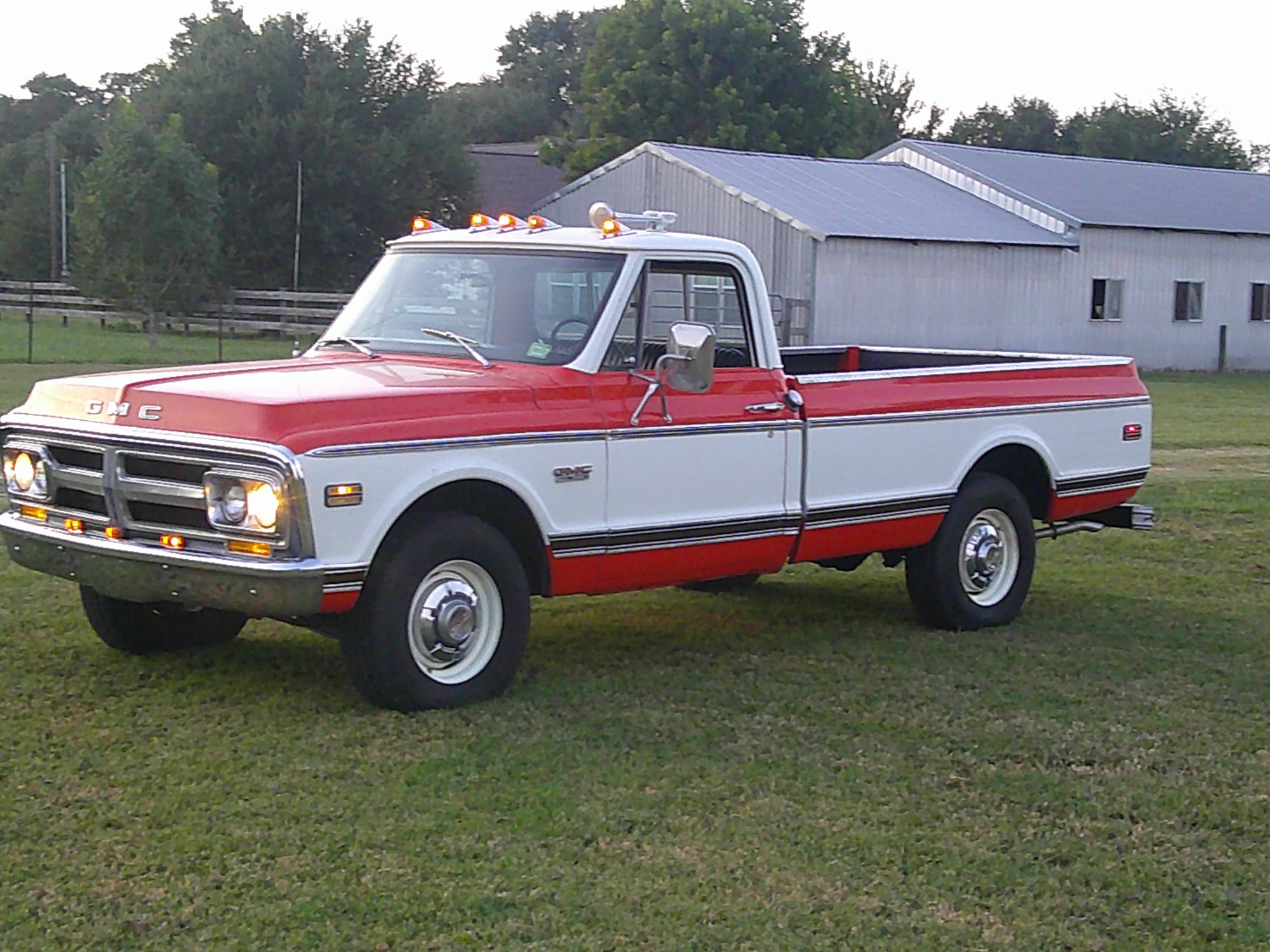 Three-quarter front view of a red and white GMC pickup truck outdoors.
