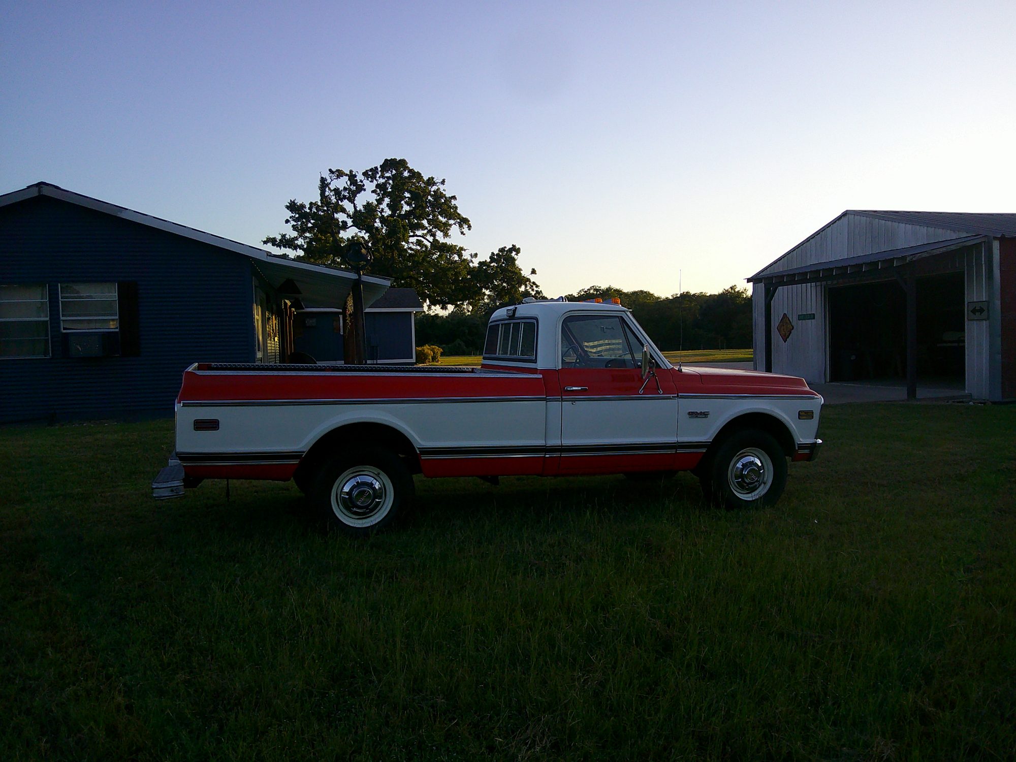 Passenger side profile of a red and white GMC pickup truck.