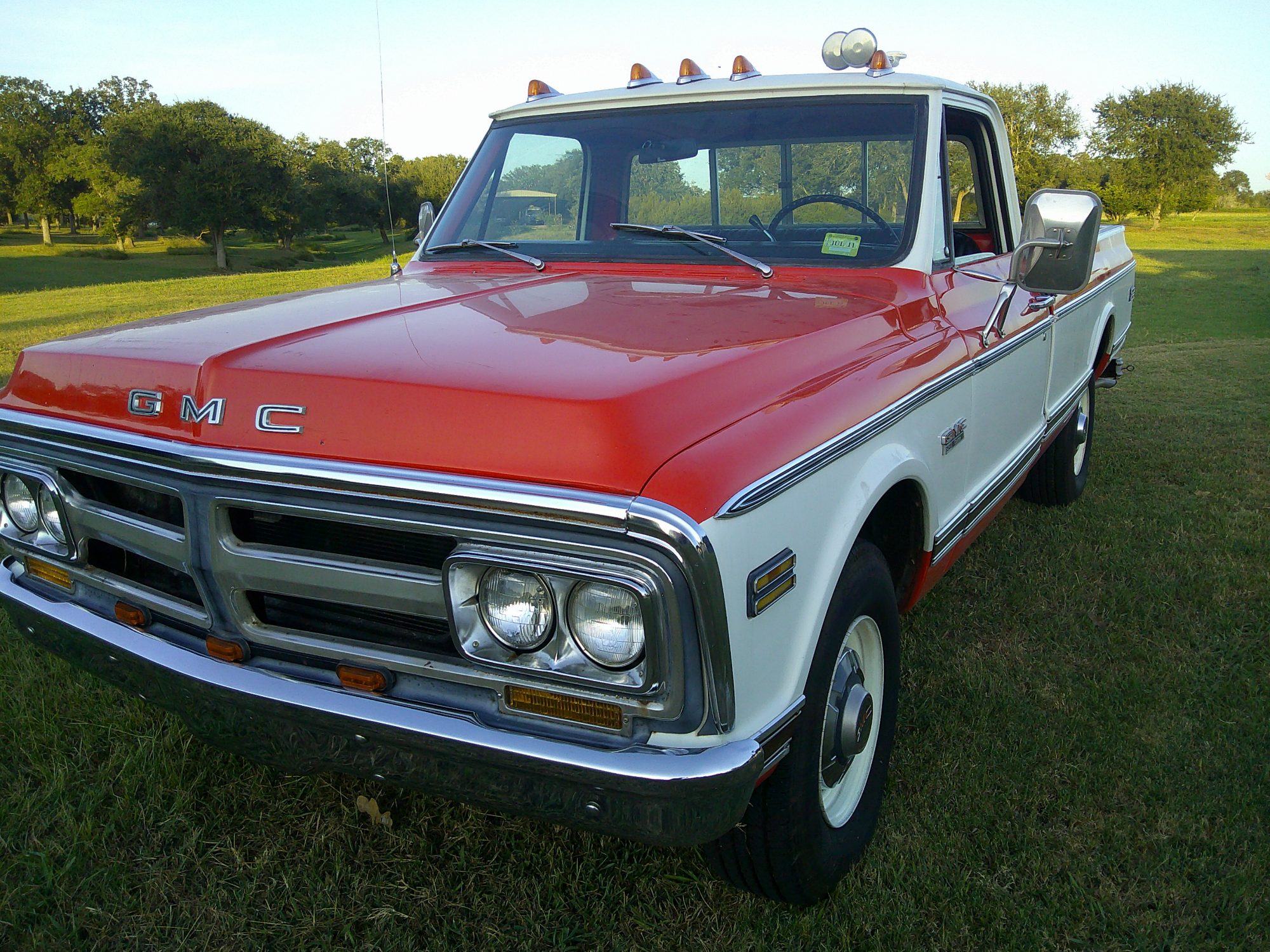 Front three-quarter view of a two-tone red and white GMC pickup truck.