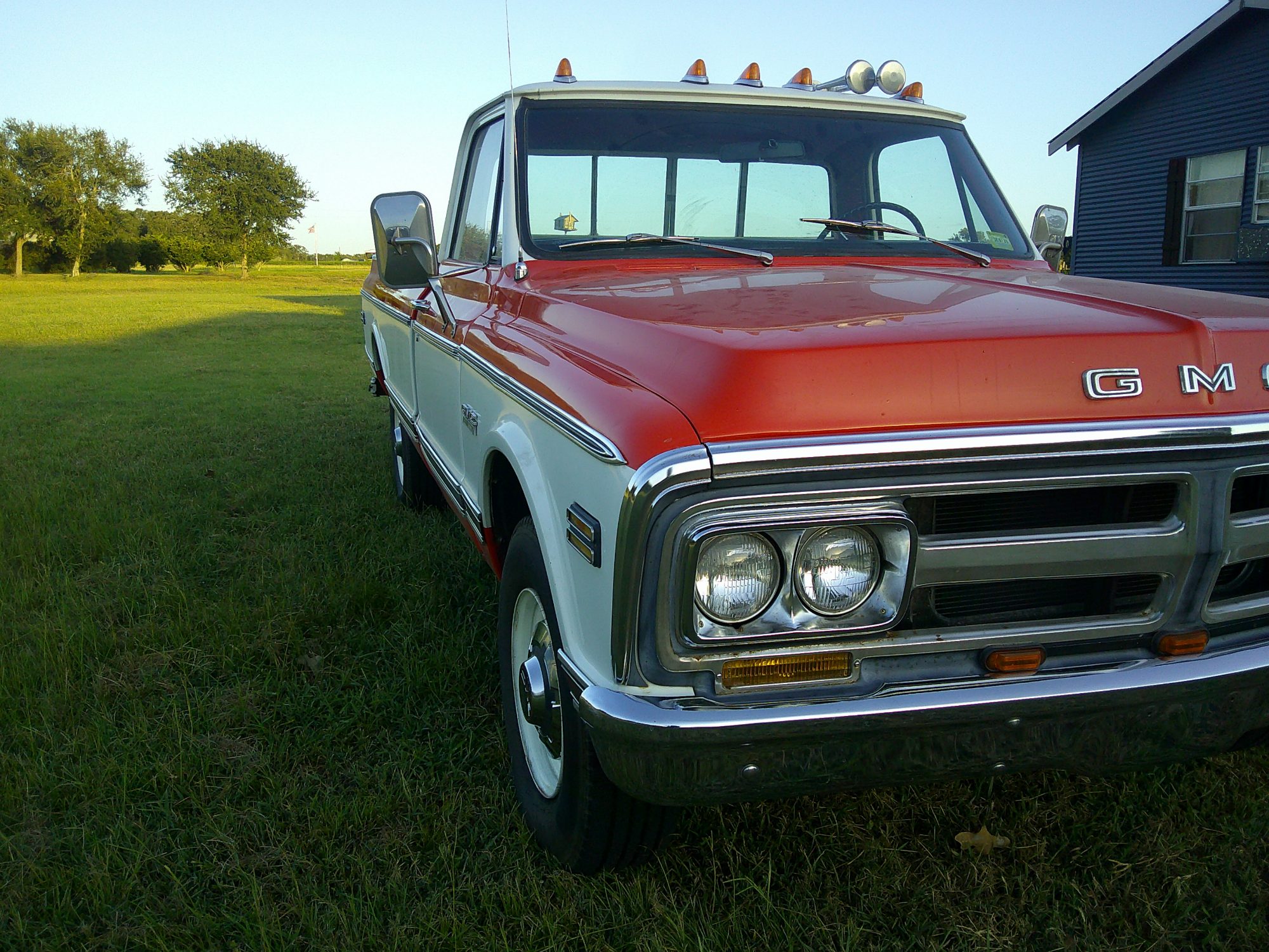 Front three-quarter view of a two-tone GMC pickup truck with quad headlights.