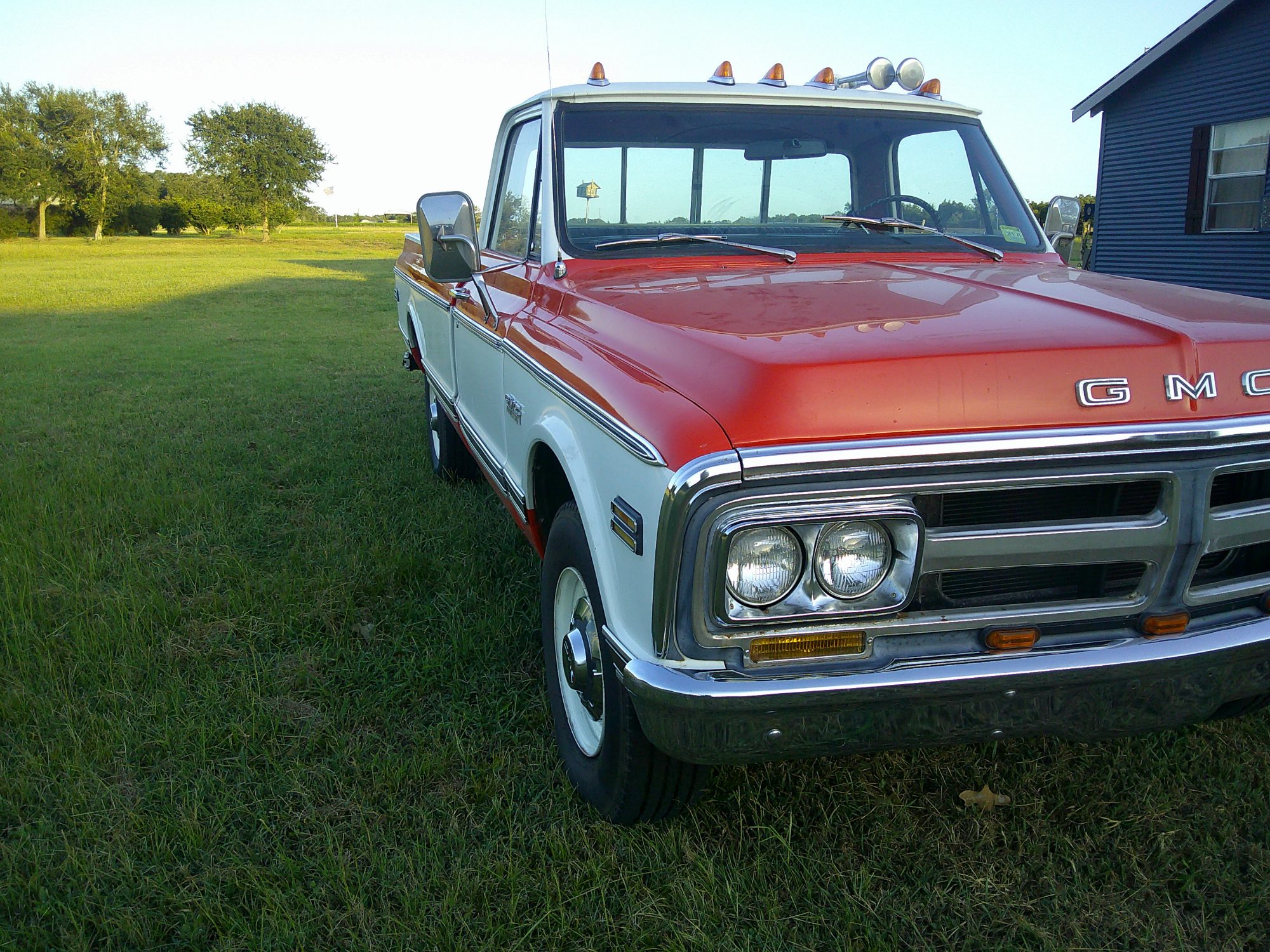 Front three-quarter view of a two-tone orange and white GMC pickup truck.