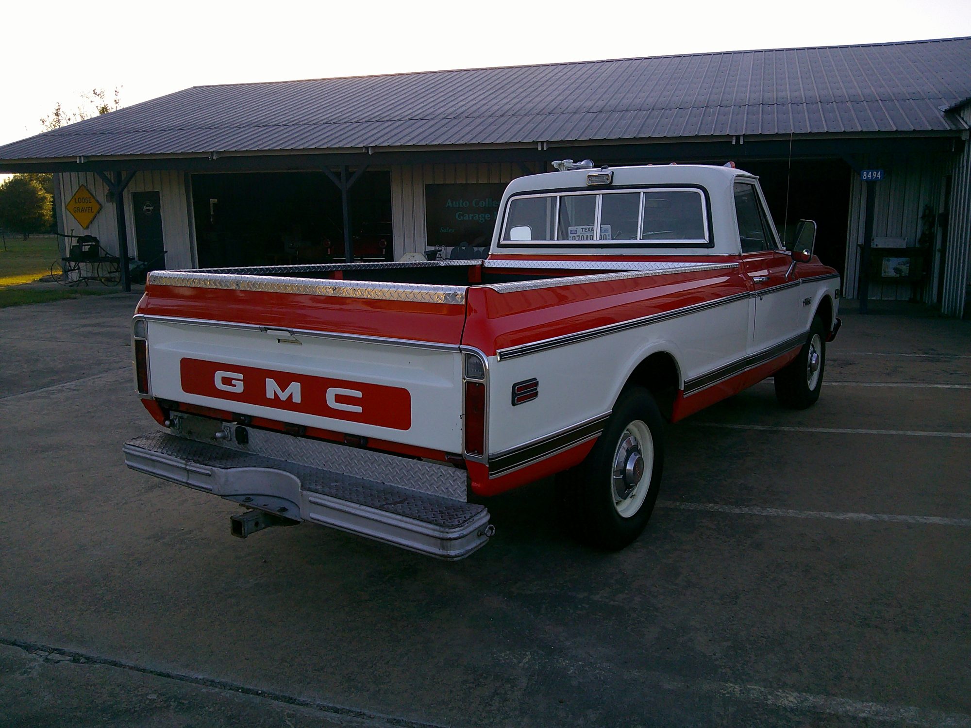 Rear three-quarter view of a two-tone red and white GMC pickup truck.