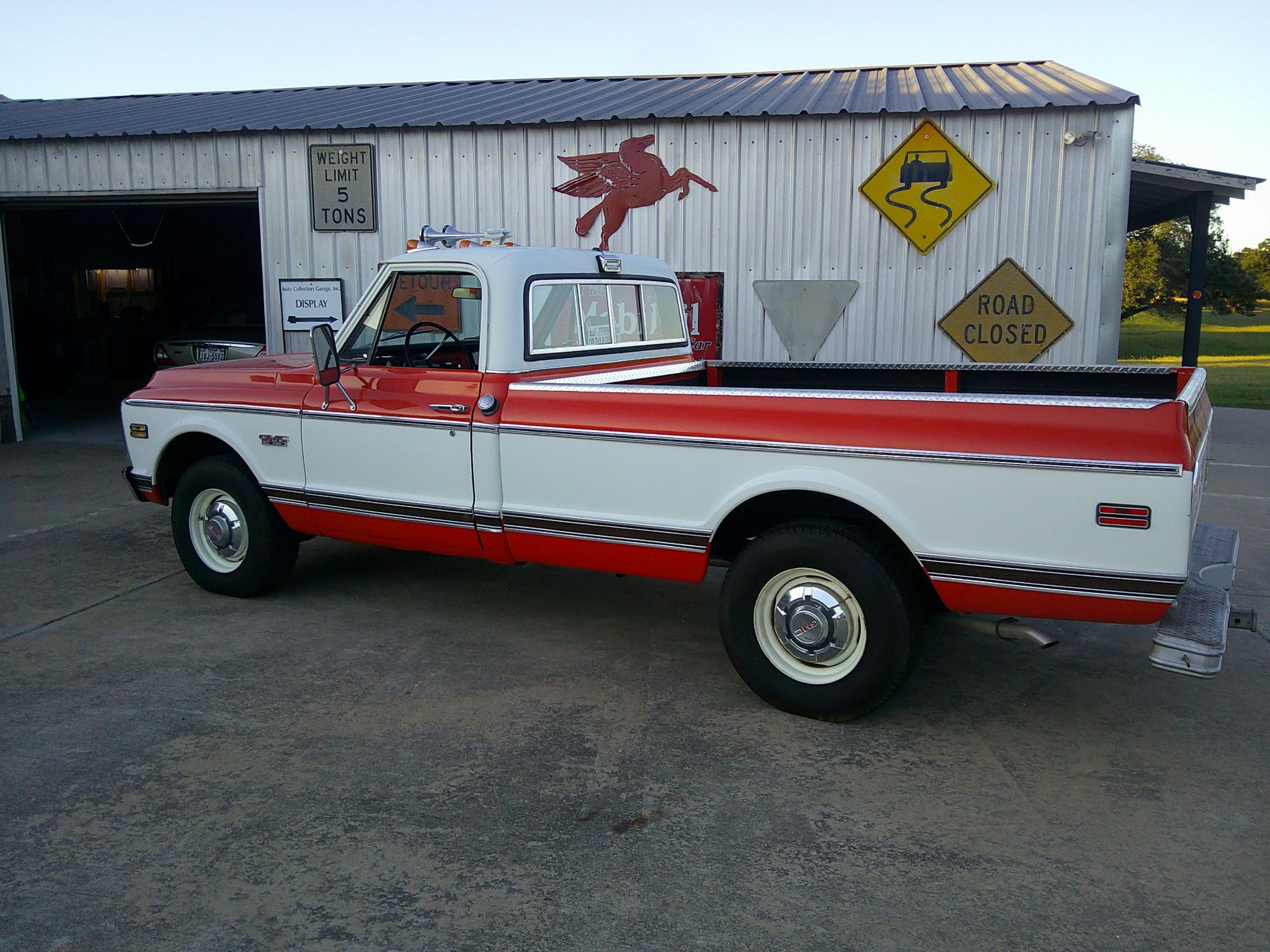Rear three-quarter view of a red and white GMC pickup truck.
