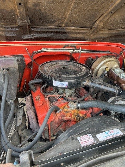 Small block V8 engine bay with black air cleaner and red valve covers.