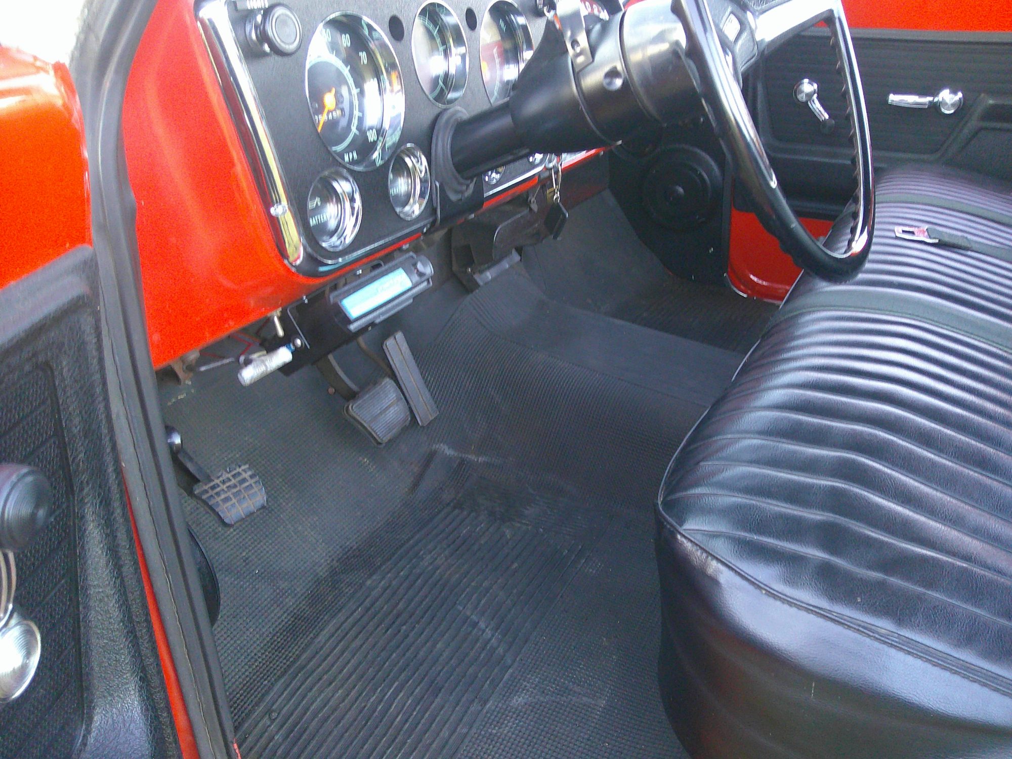 View of the dashboard, steering wheel, and vinyl bench seat from the driver's side.