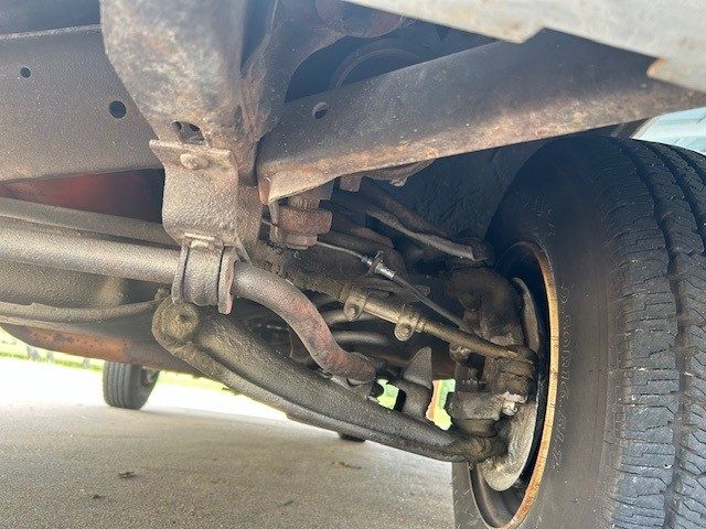 Underbody view of front suspension, chassis frame, and inner wheel well.