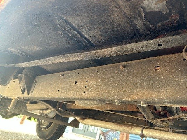 Underbody view of chassis frame, exhaust pipe, and rear wheel